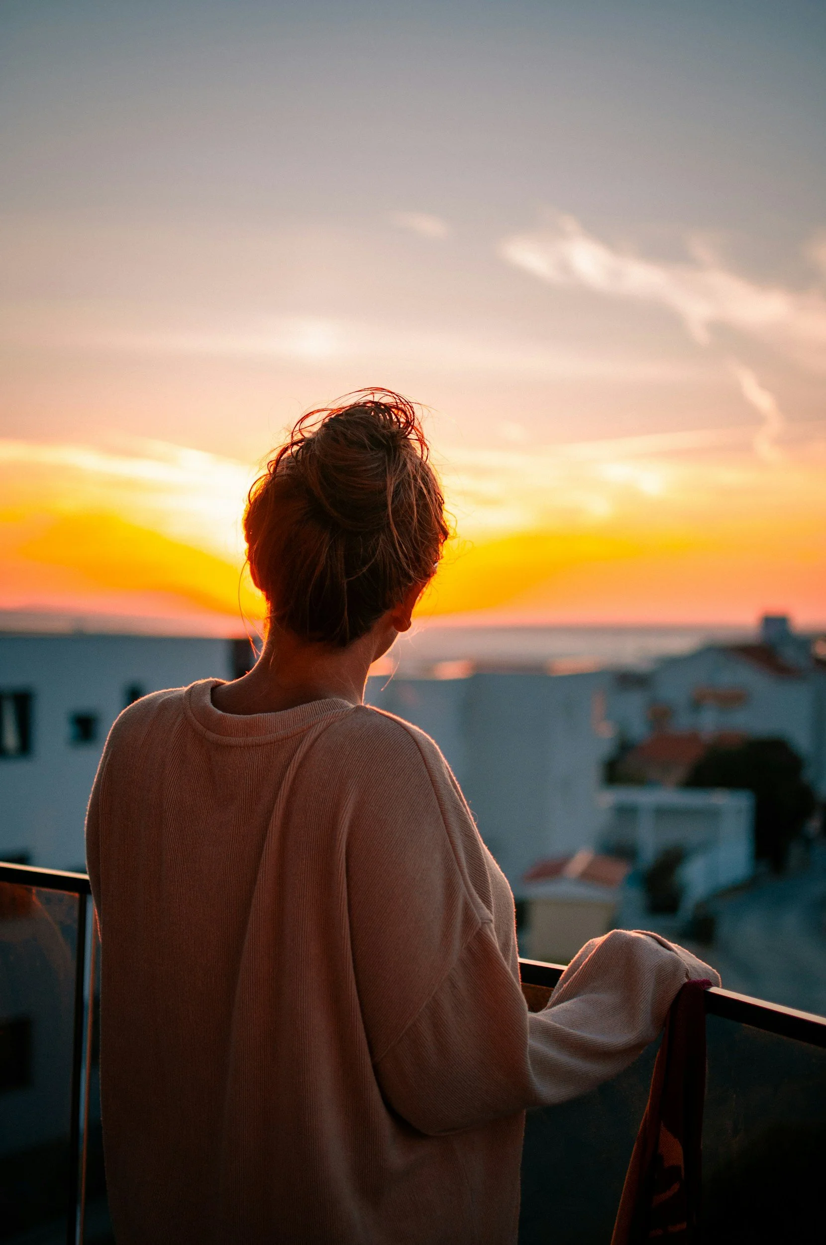 Person standing on balcony watching sunset. Therapy for young adults, support for navigating adulthood in Mill Valley, CA