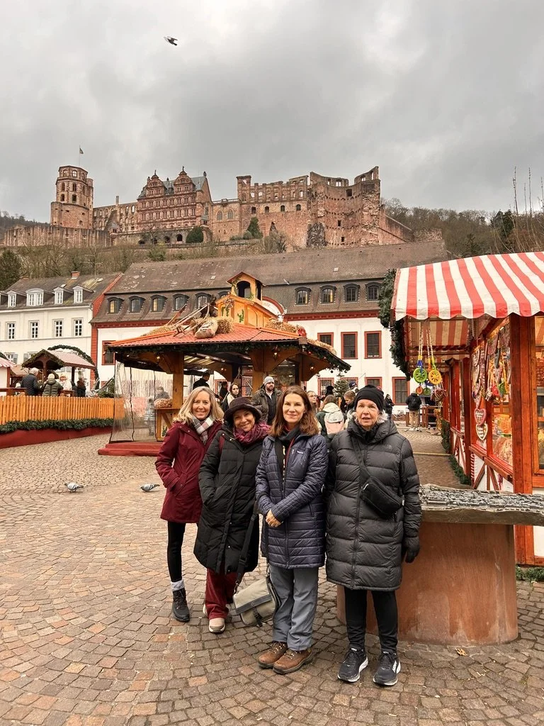 Four Dandelion Journals travelers together in a German town square with a castle lit on the hill behind them