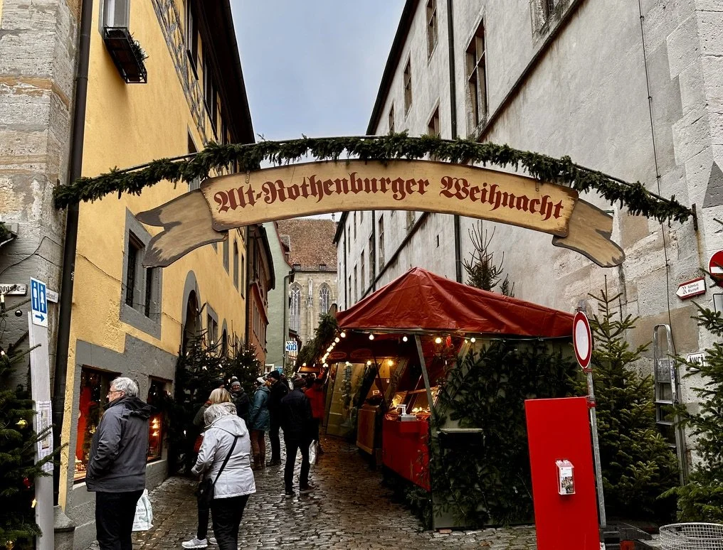 A Christmas market street in Rothenburg ob der Tauber, stalls decorated and lit at dusk