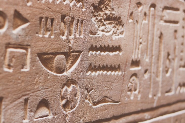 Carved hieroglyphs in warm sandstone on a temple wall