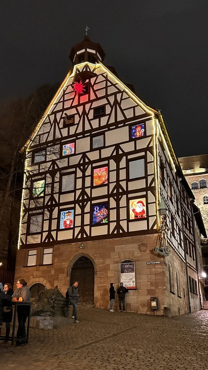 A half-timbered German building strung with Christmas lights after dark