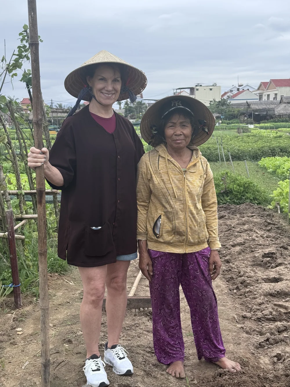 Two travelers in wide straw hats among the vegetable beds