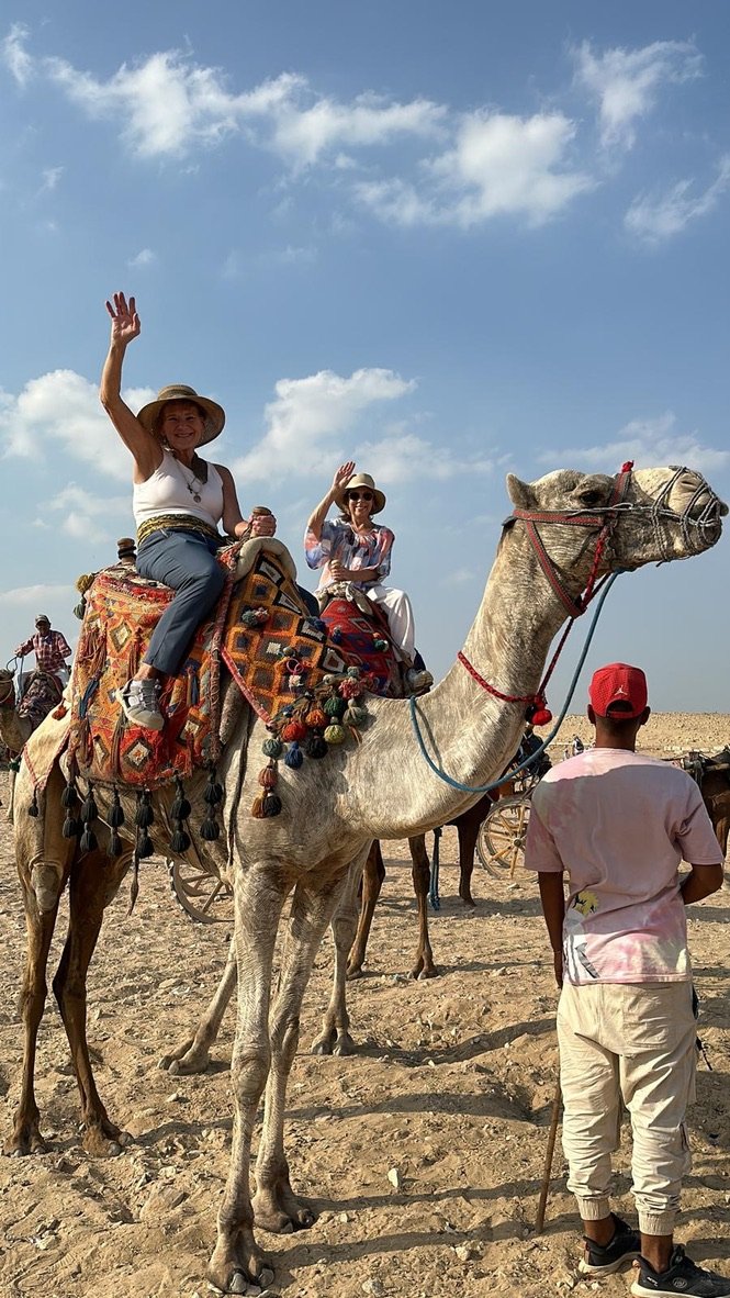 Travelers riding a camel on the Giza plateau near the pyramids