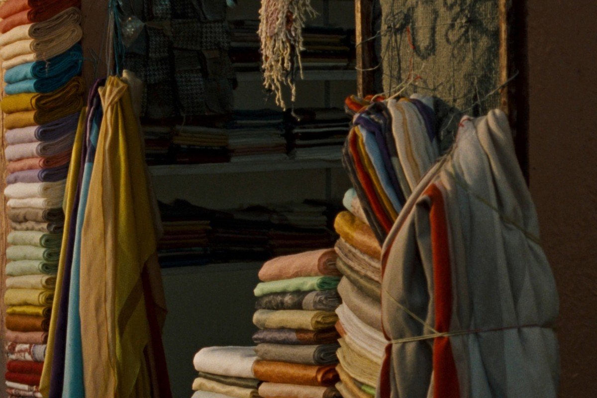 Stacks of folded Moroccan scarves in a sunlit souk stall
