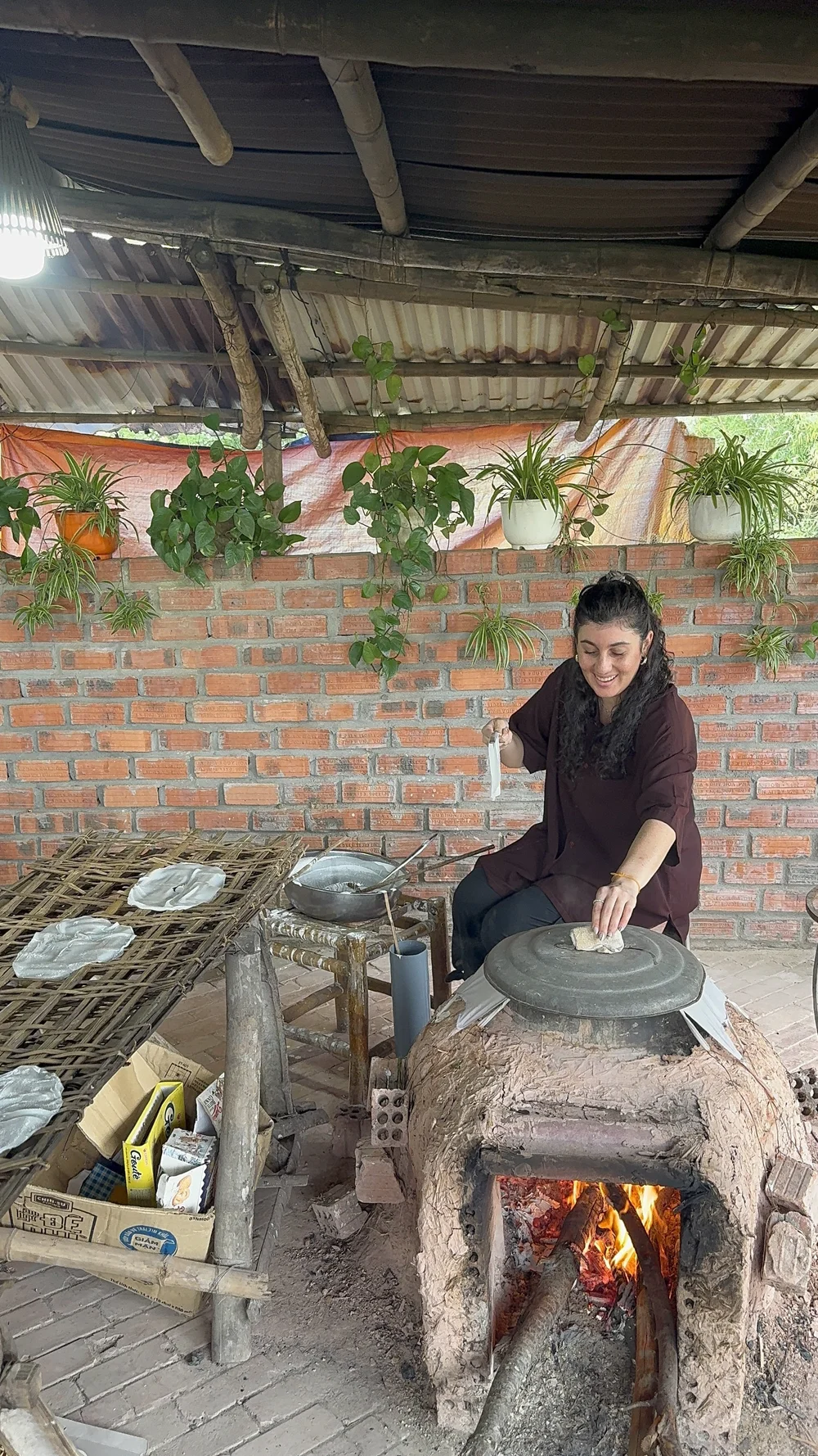 A woman cooking over a traditional clay stove during a hands-on class