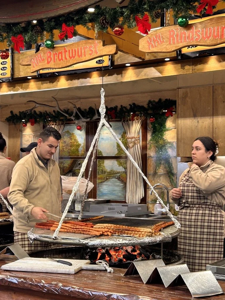 Sausages cooking over an open flame at a Christmas market grill stand