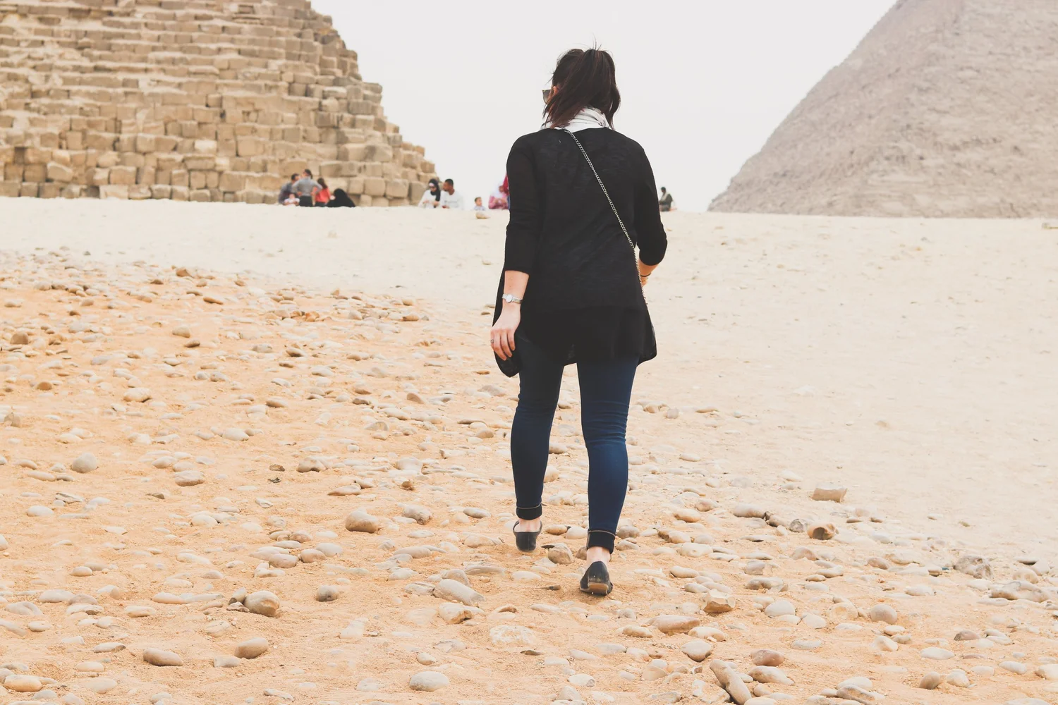 A traveler walking across the sand toward the Great Pyramid