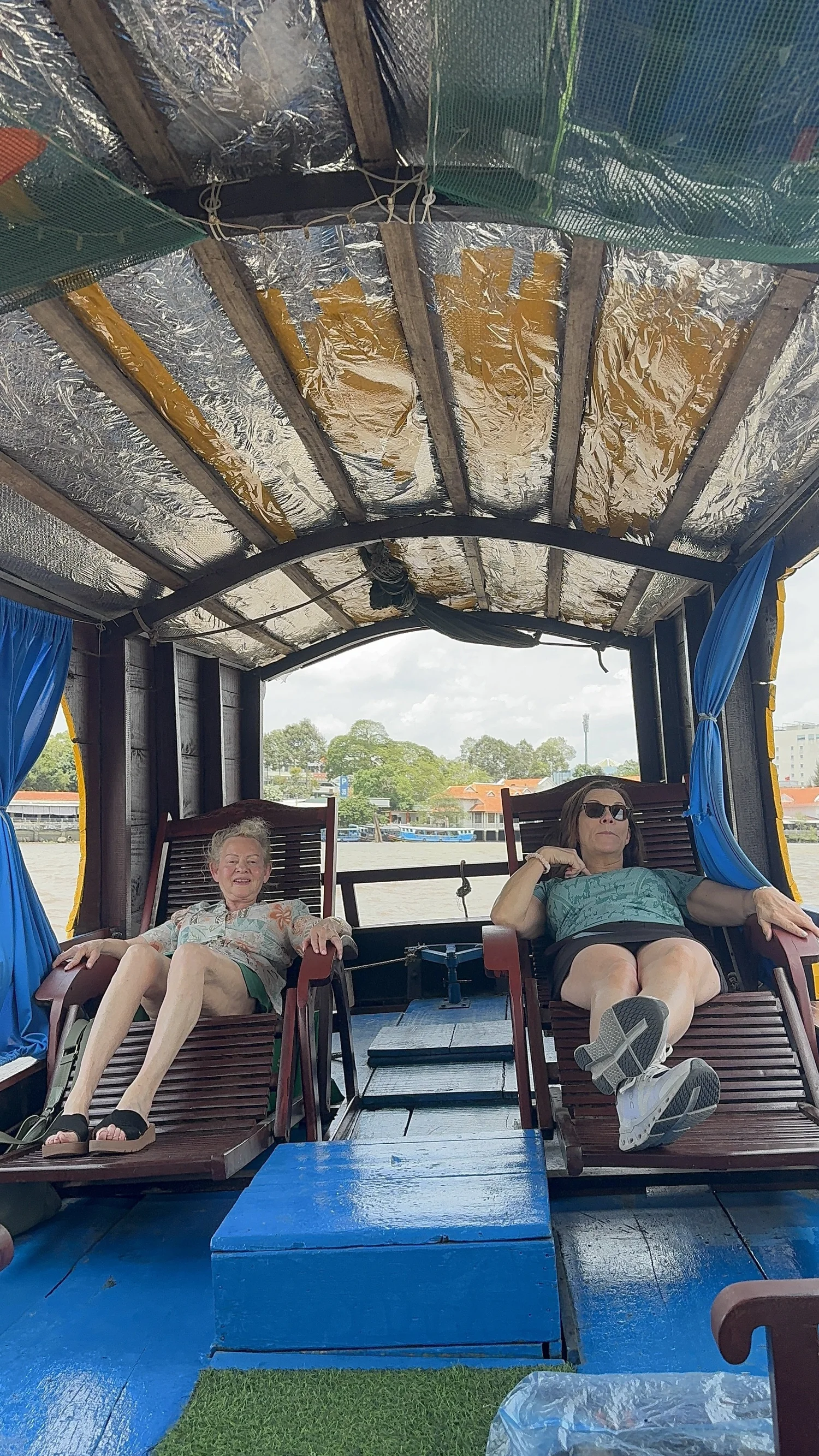 Dandelion Journals travelers relaxing on wooden loungers aboard the cruise, the waters of Ha Long Bay beyond