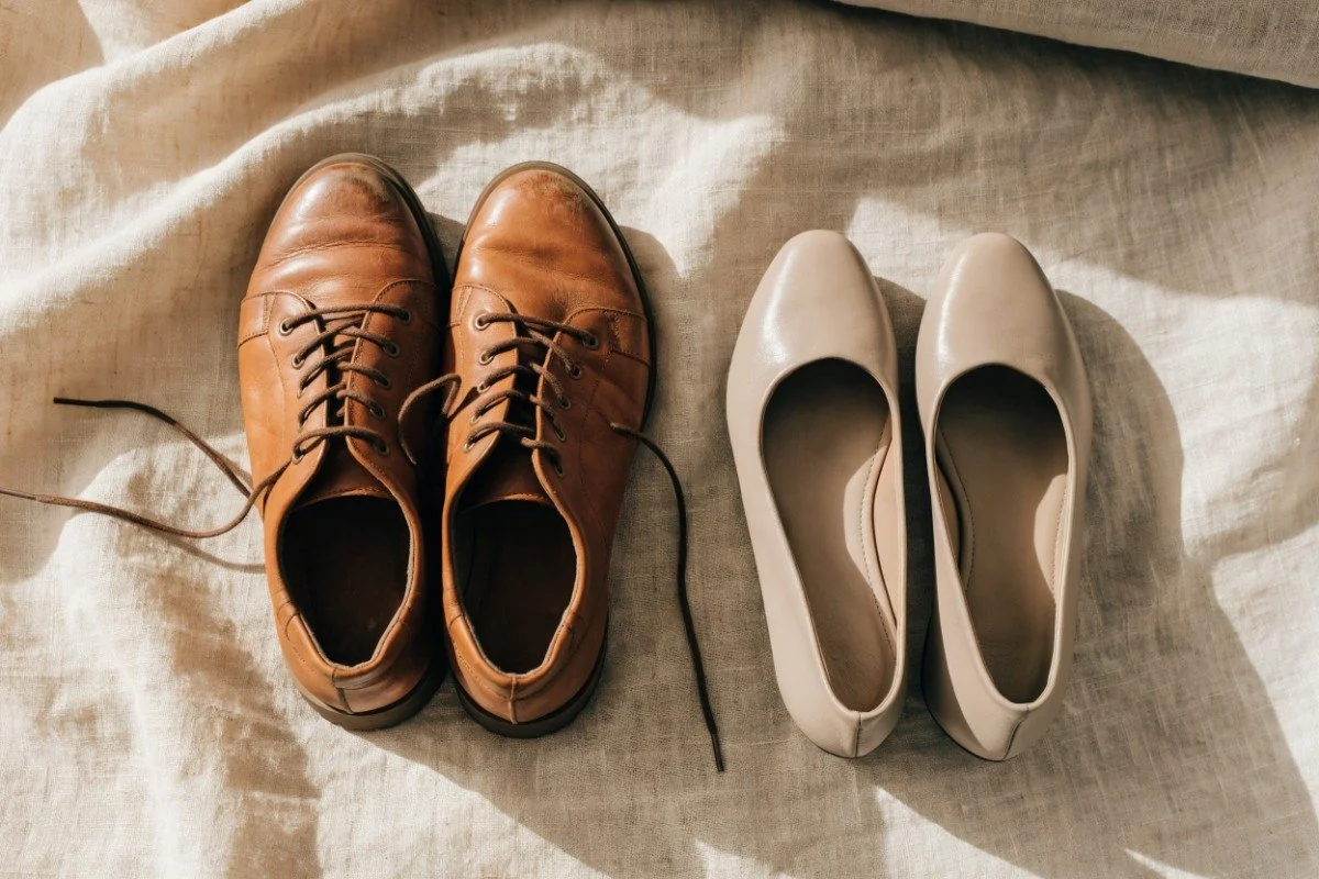 Broken-in tan leather walking shoes beside a pair of neutral flats for dinner