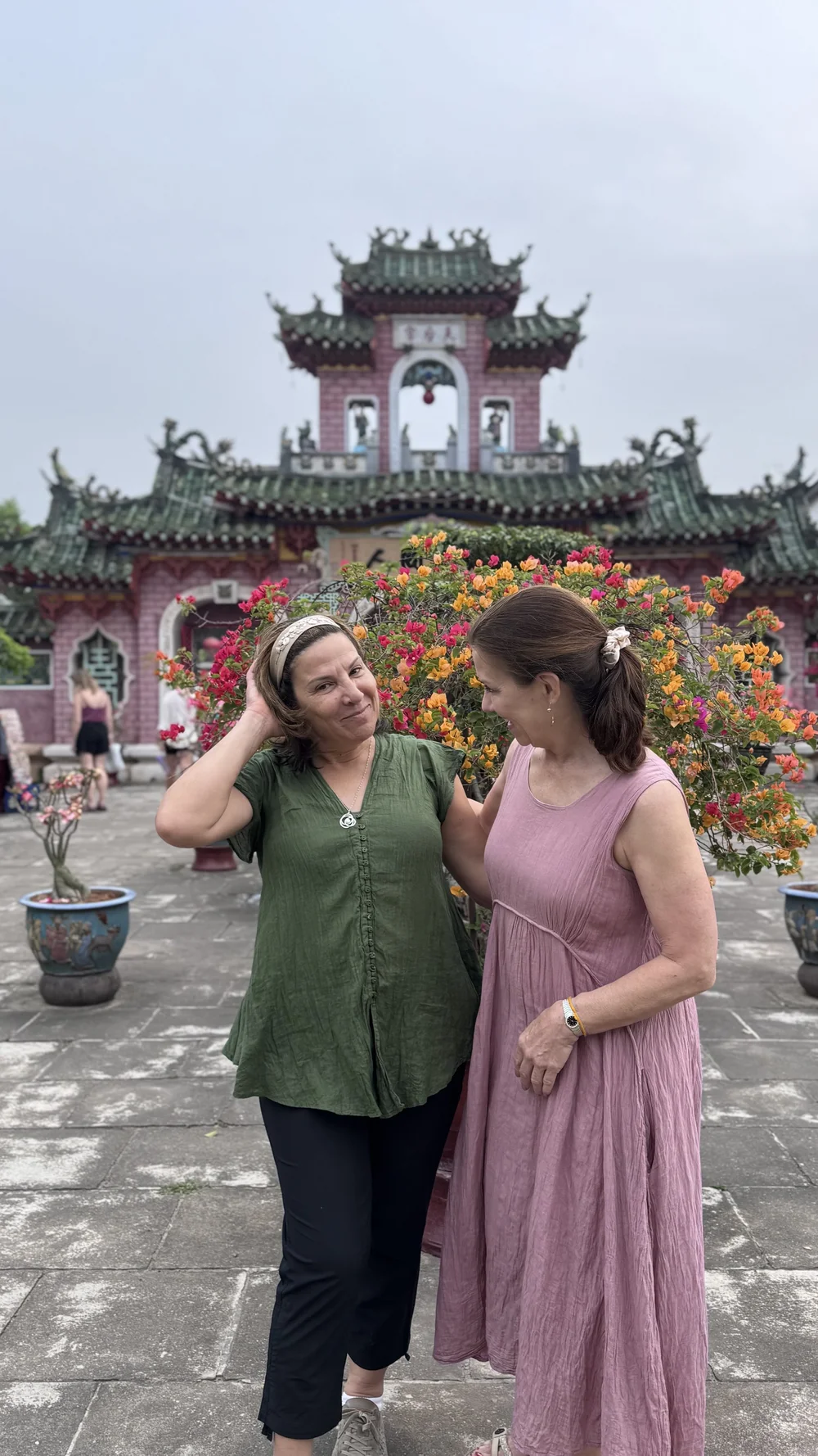 Two travelers in front of a pink temple with colourful detailing