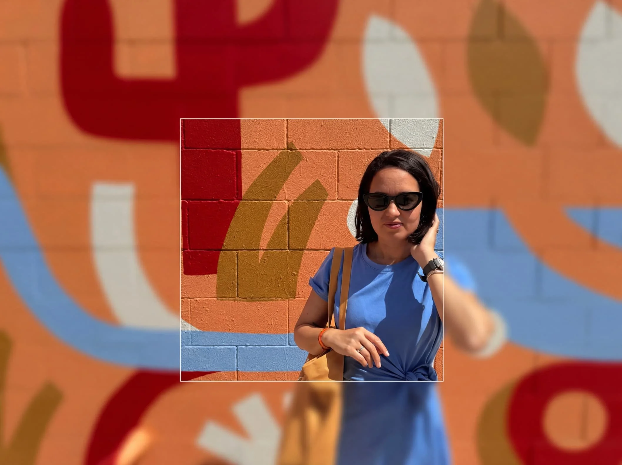 Heloise Ralanto, co-founder of Après-Midi Agency, wearing sunglasses and a blue shirt, standing in front of a colorful Palm Springs mural painted on a brick wall with red, orange, and blue sections.