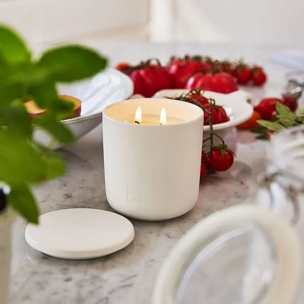 Moisturizer jar on vanity table with soft towel and candle.