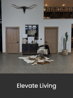Interior of a modern living space with two closed wooden doors, a black console table with decorative items and a mirror, a cowhide rug on the floor, a beige armchair, and a tall cactus plant in a pot. A wall-mounted decorative bull skull hangs above the doors.