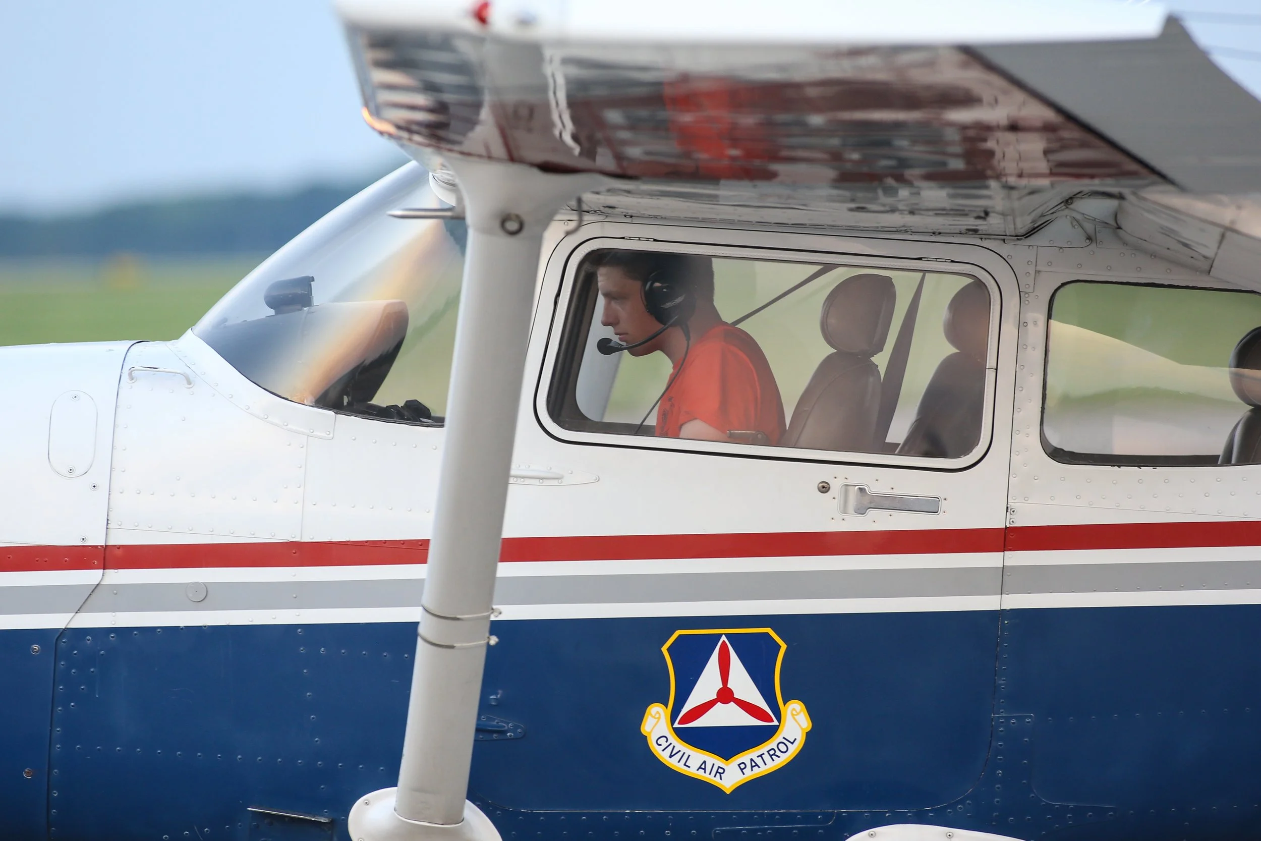 A young male cadet wearing a headset inside a Civil Air Patrol aircraft cockpit during CAP's Flight Academy.