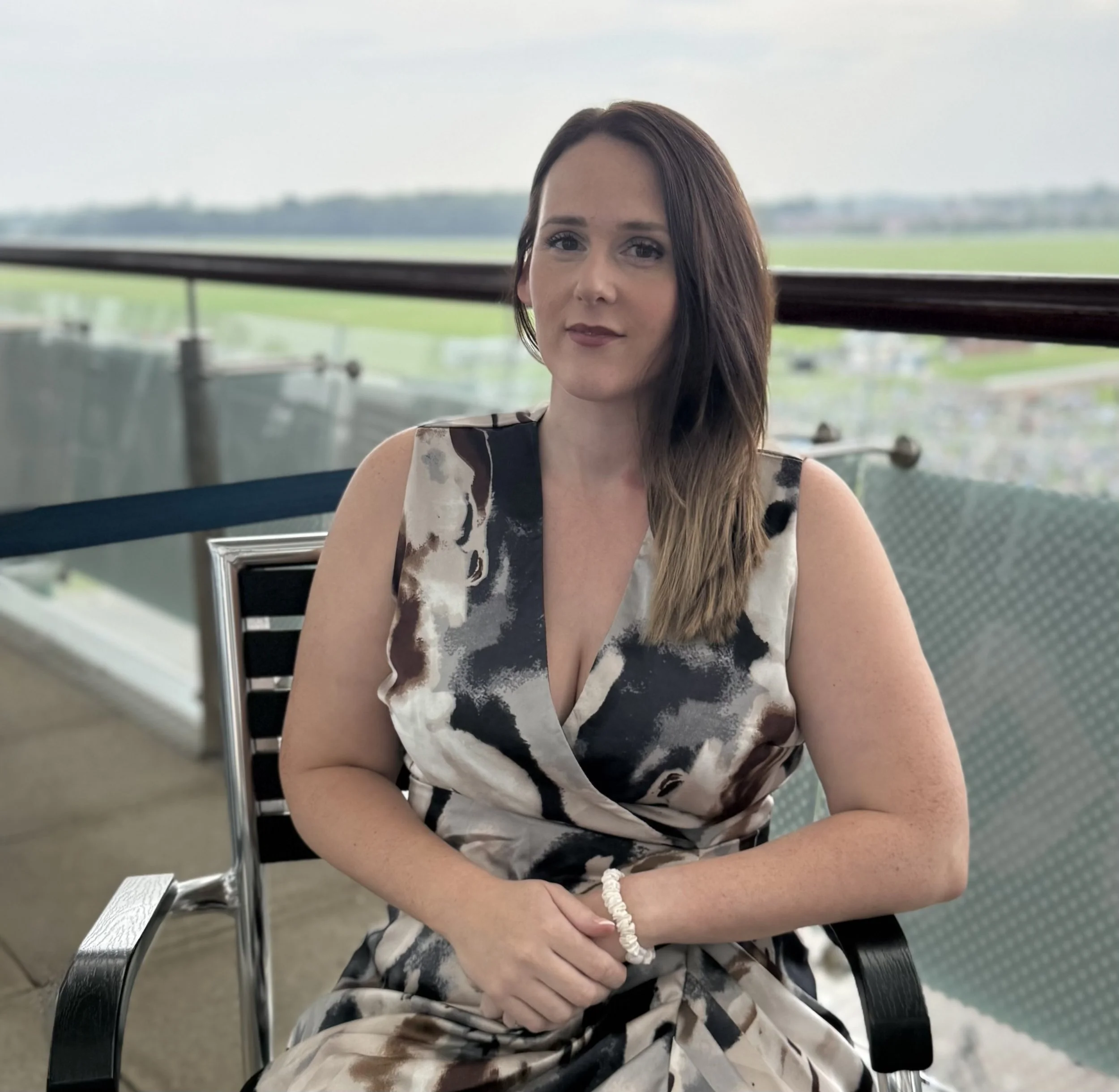 Female with short blonde hair, wearing a floral black and white top