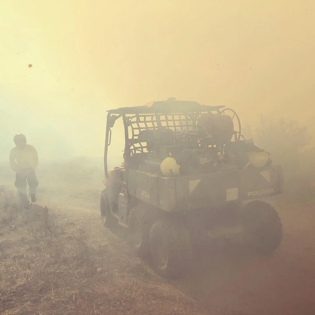 Wildland firefighter standing next to a UTV in heavy smoke