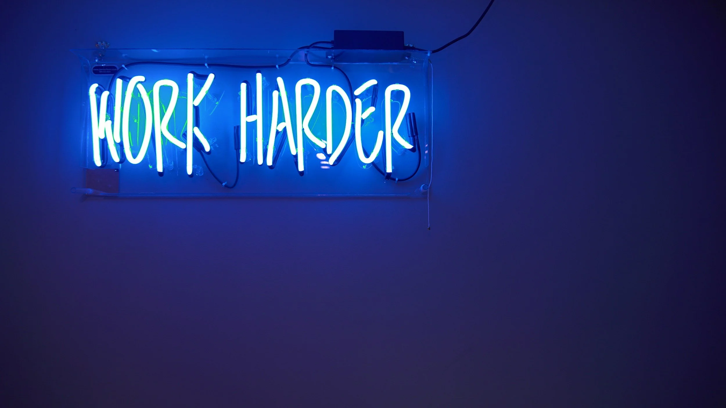 Neon sign that says "Work harder"
