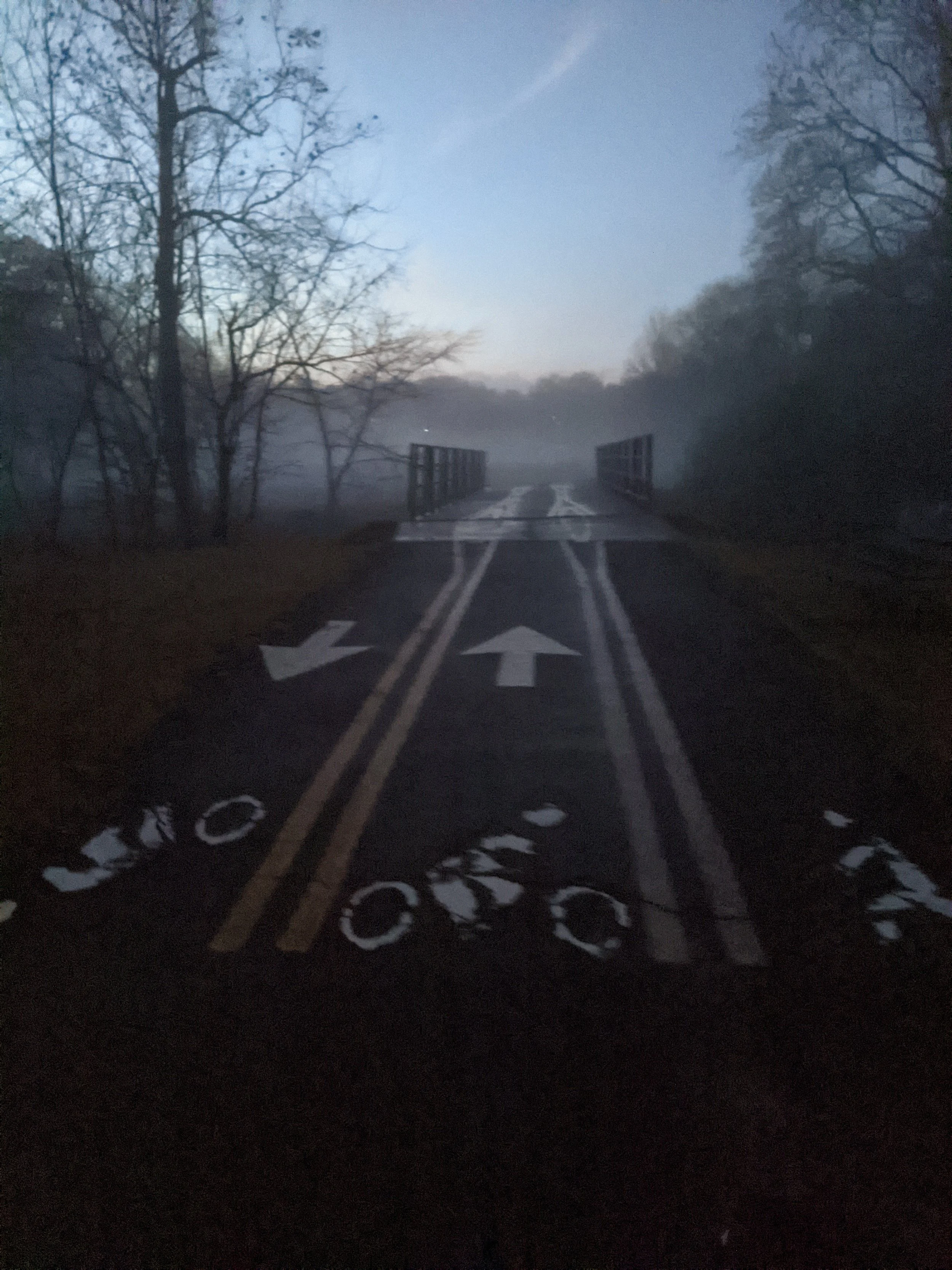 Bike path and walkway passing over a bridge in dense fog.