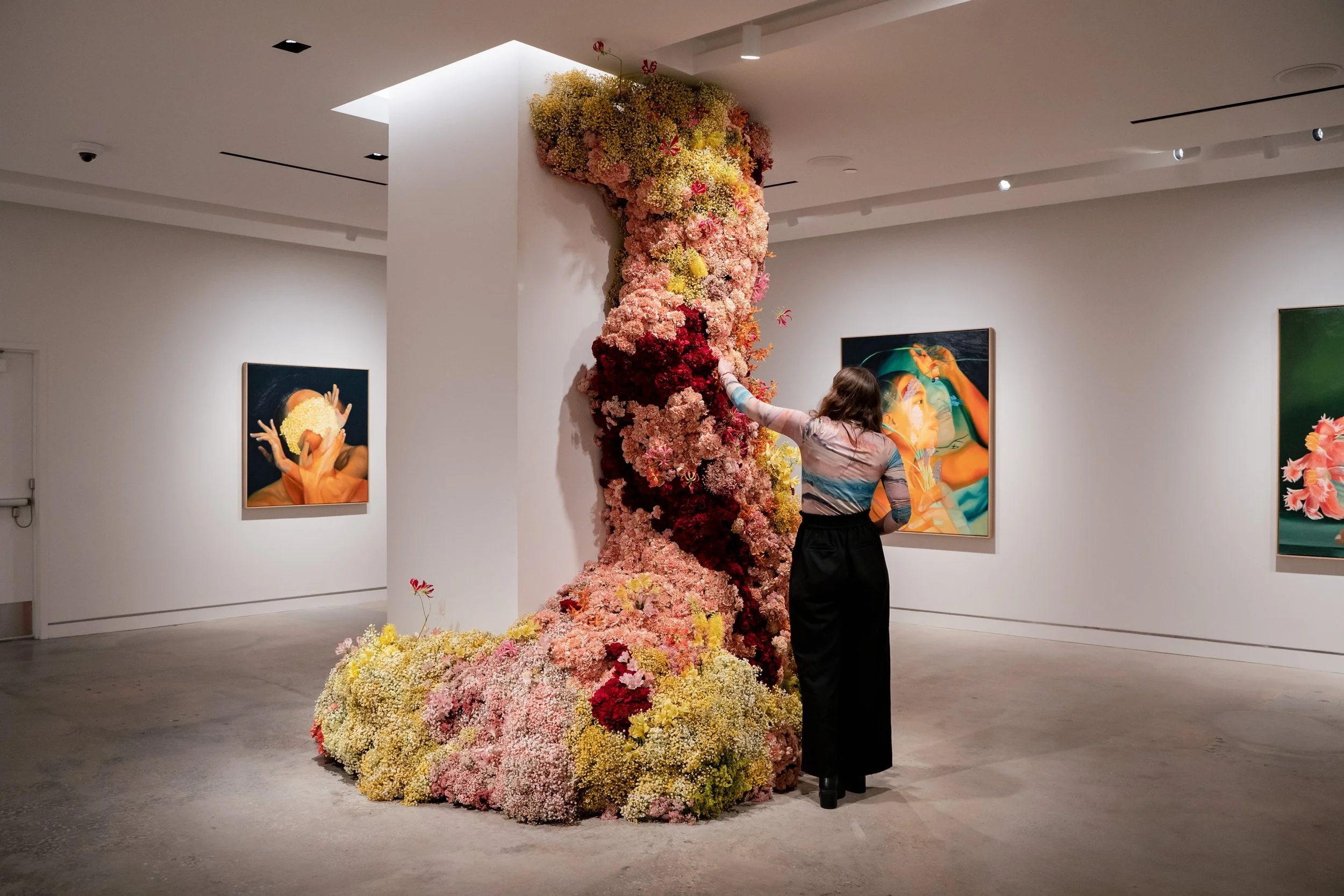 Group of diverse women smiling and laughing at a social gathering, some holding party hats and balloons, with colorful wall art in the background.