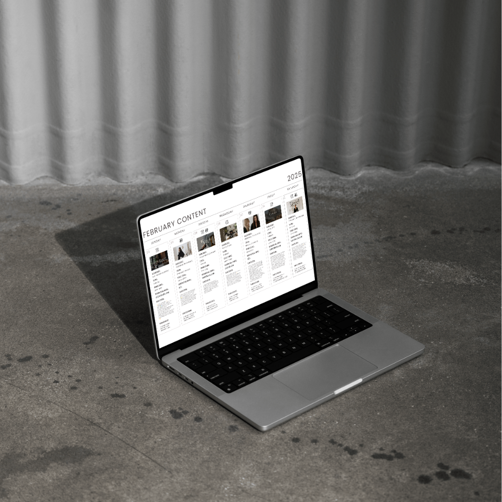Open laptop on concrete floor displaying a content calendar for February 2025 on the screen.