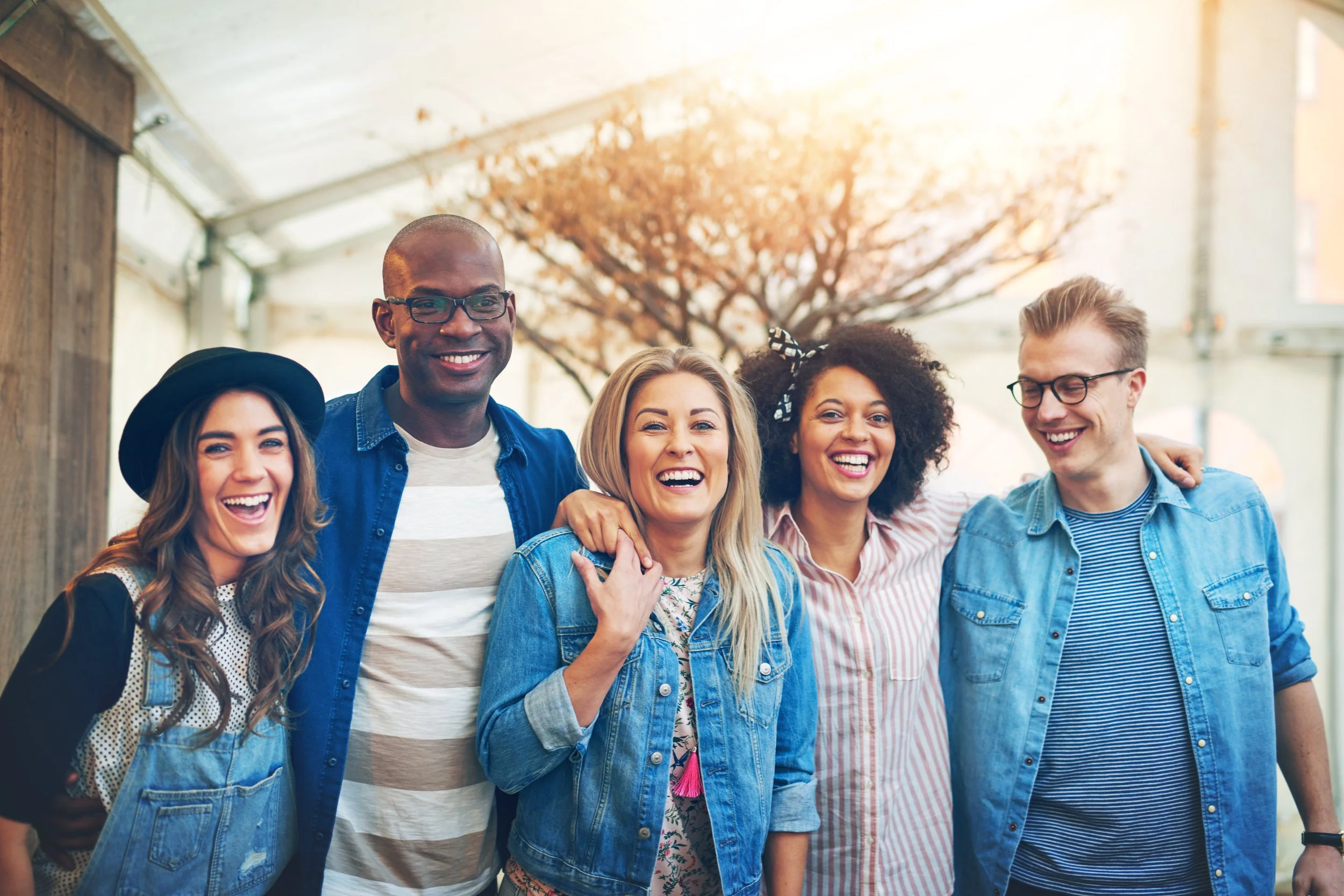 Group of five friends smiling and posing together indoors in casual clothing.