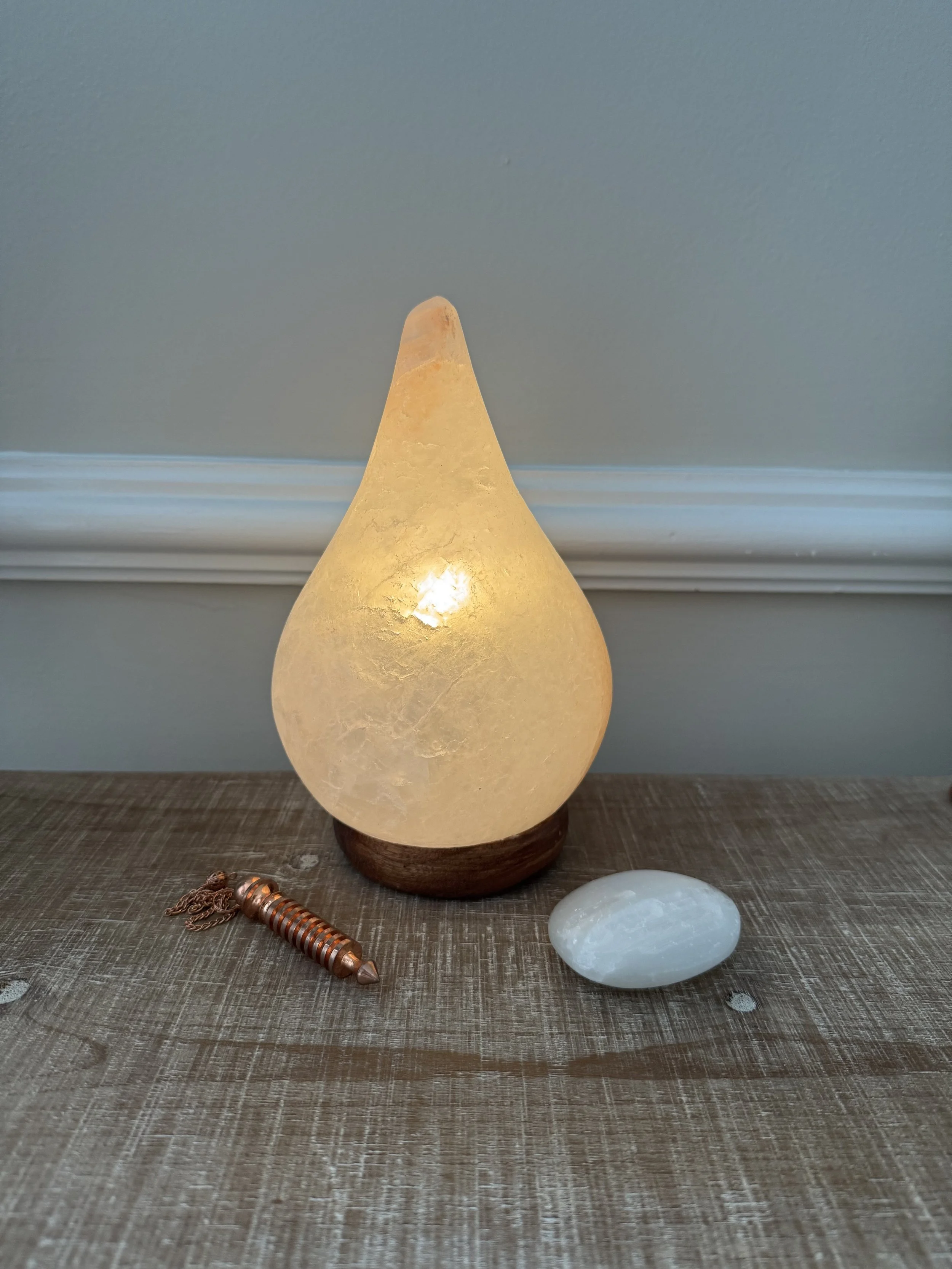 Himalayan salt lamp, selenite crystal, and pendulum used in Reiki energy healing sessions in Augusta, GA.