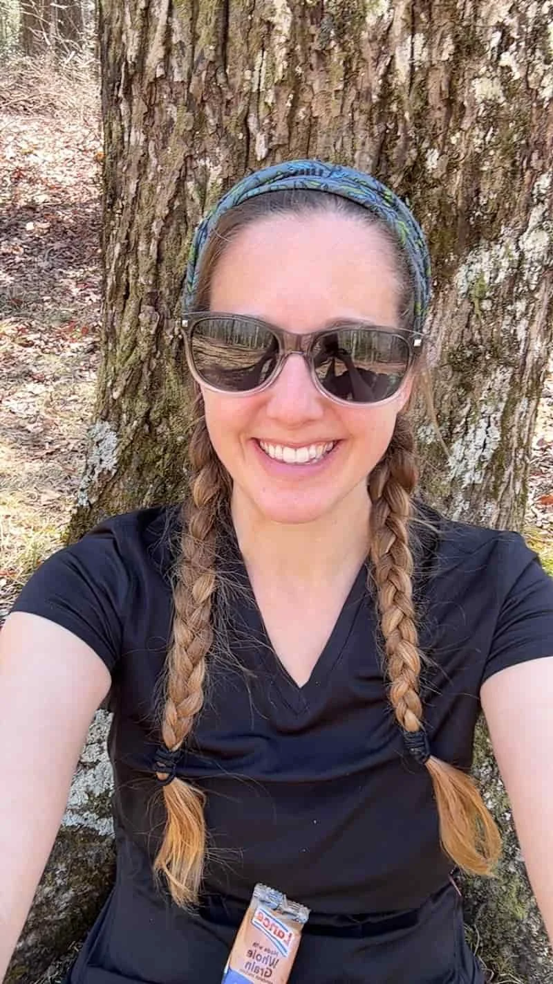 Becca Morris, Counselor & Reiki Master in Augusta, GA, taking a break from a hike to rest on a tree.