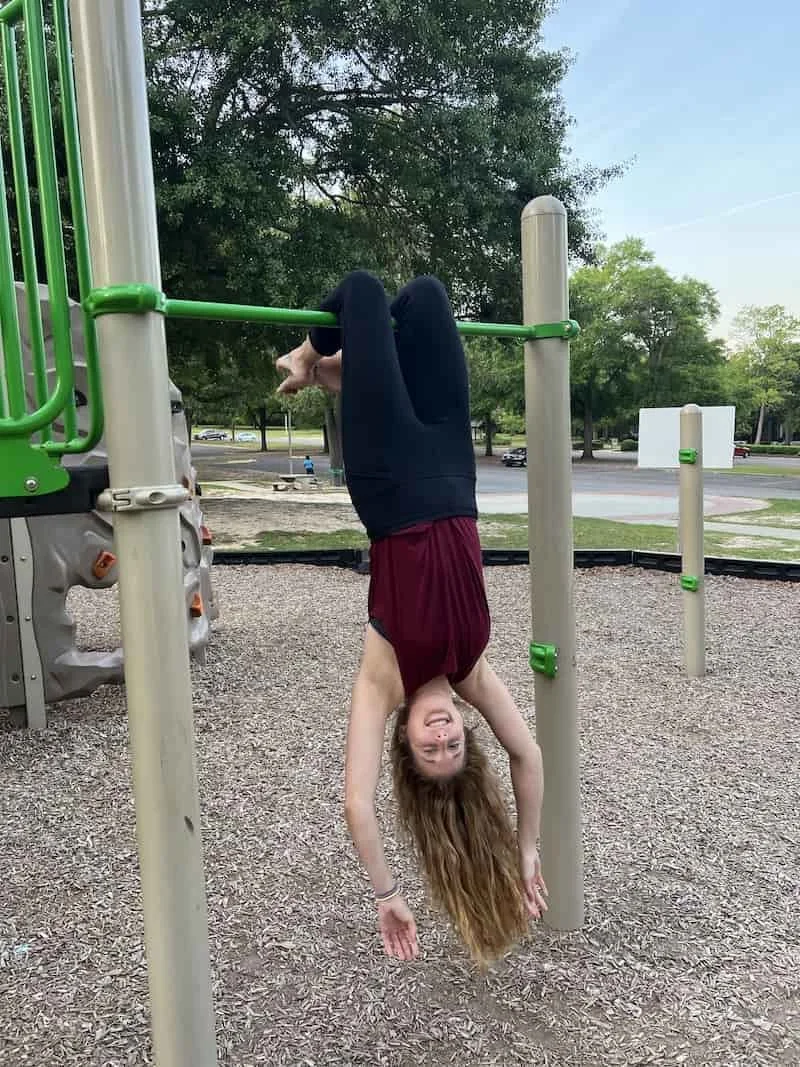 Becca Morris, Counselor and Reiki Master, in Augusta, GA, enjoying a playful moment hanging upside down as a reminder to change her perspective.