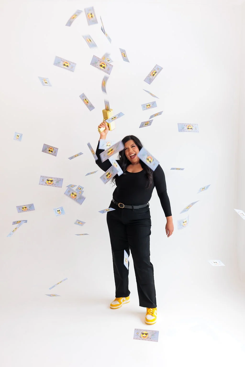Bookkeeping and business coach for service based business owners. Woman in black clothes celebrating and throwing fake dollar bills in the air against a white background.