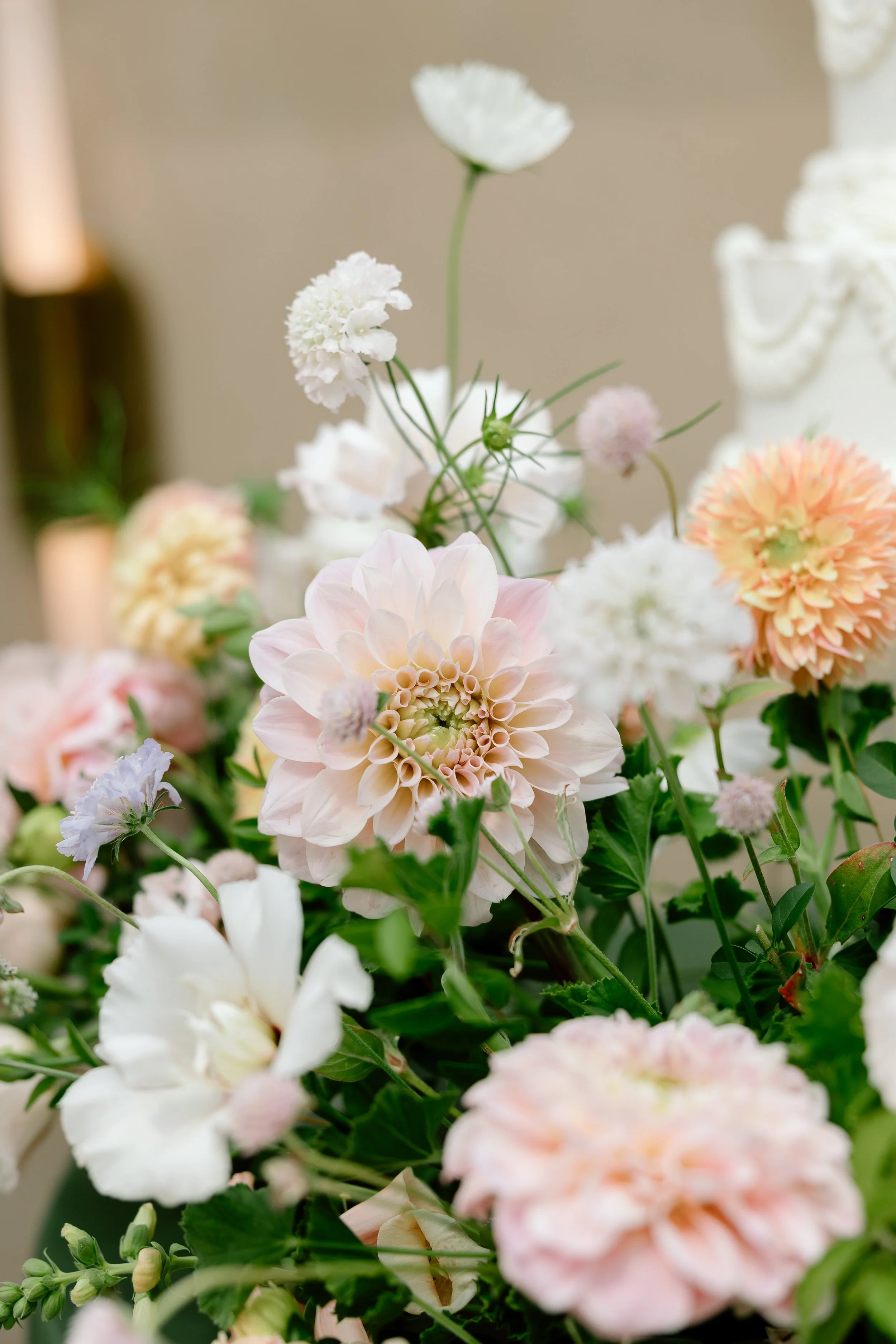A bouquet of pastel-colored flowers including dahlias, coxcomb, and various white blooms.