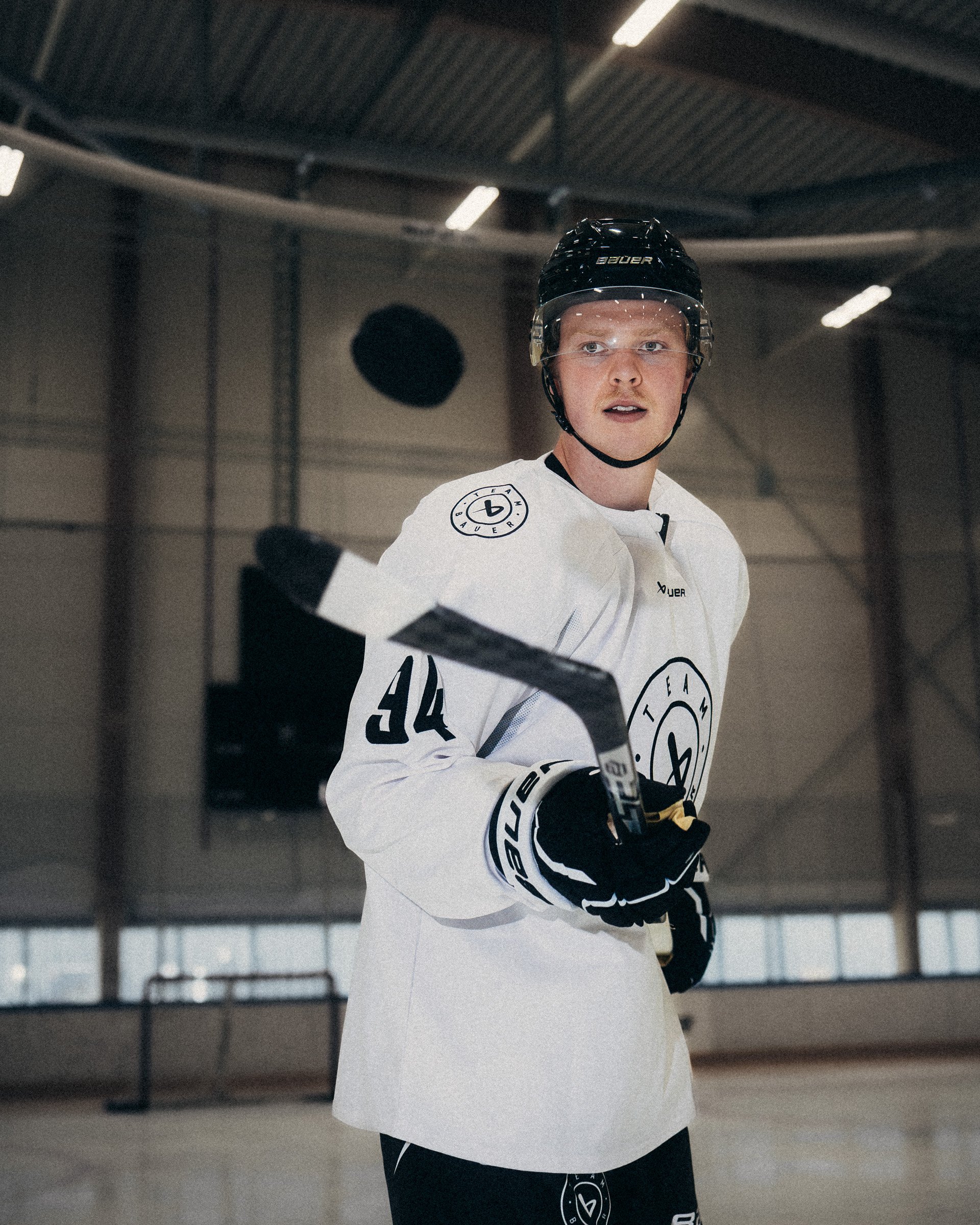 Hockey player in white jersey and black helmet on ice rink