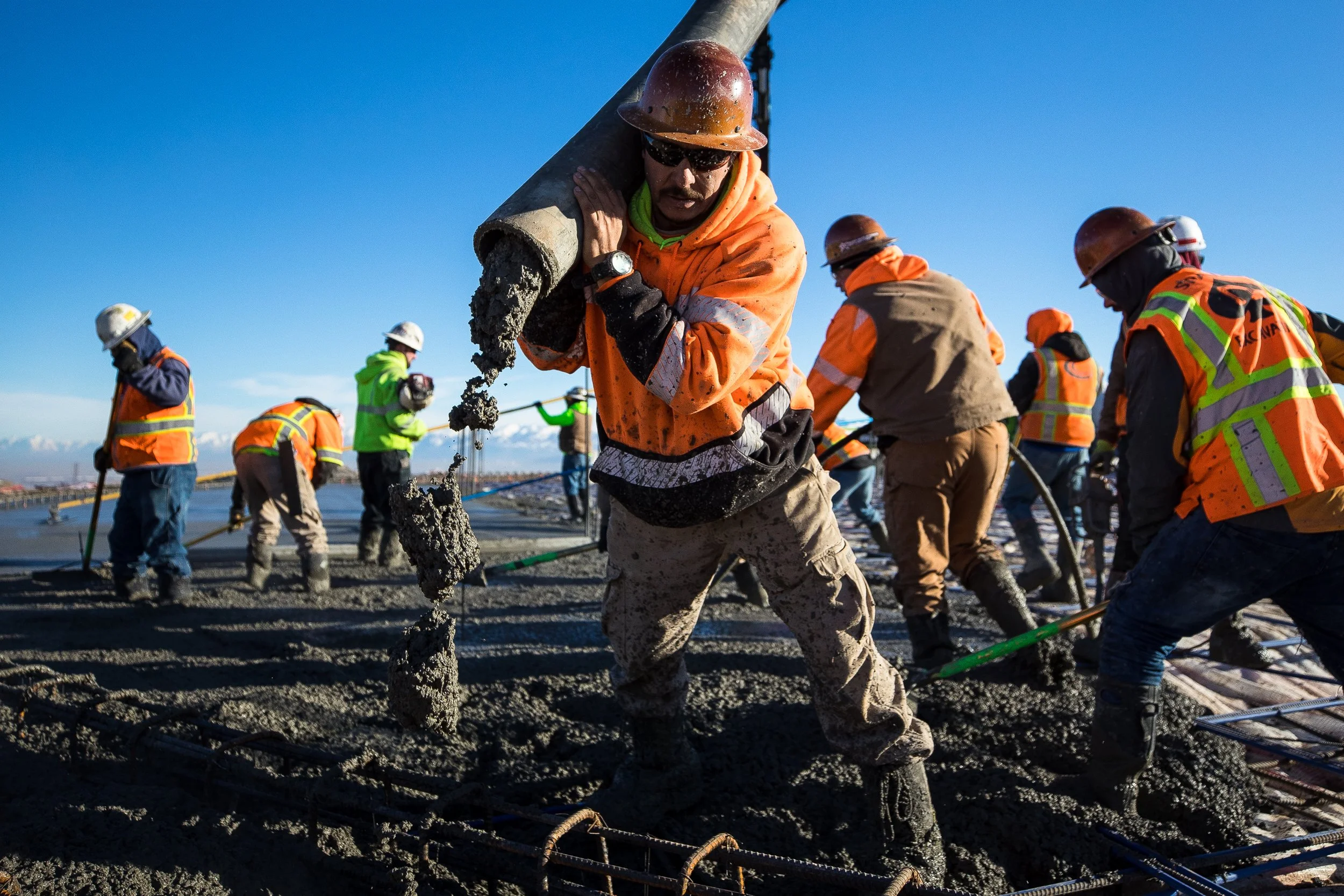 Construction workers pouring concrete on a site with rebar grid.