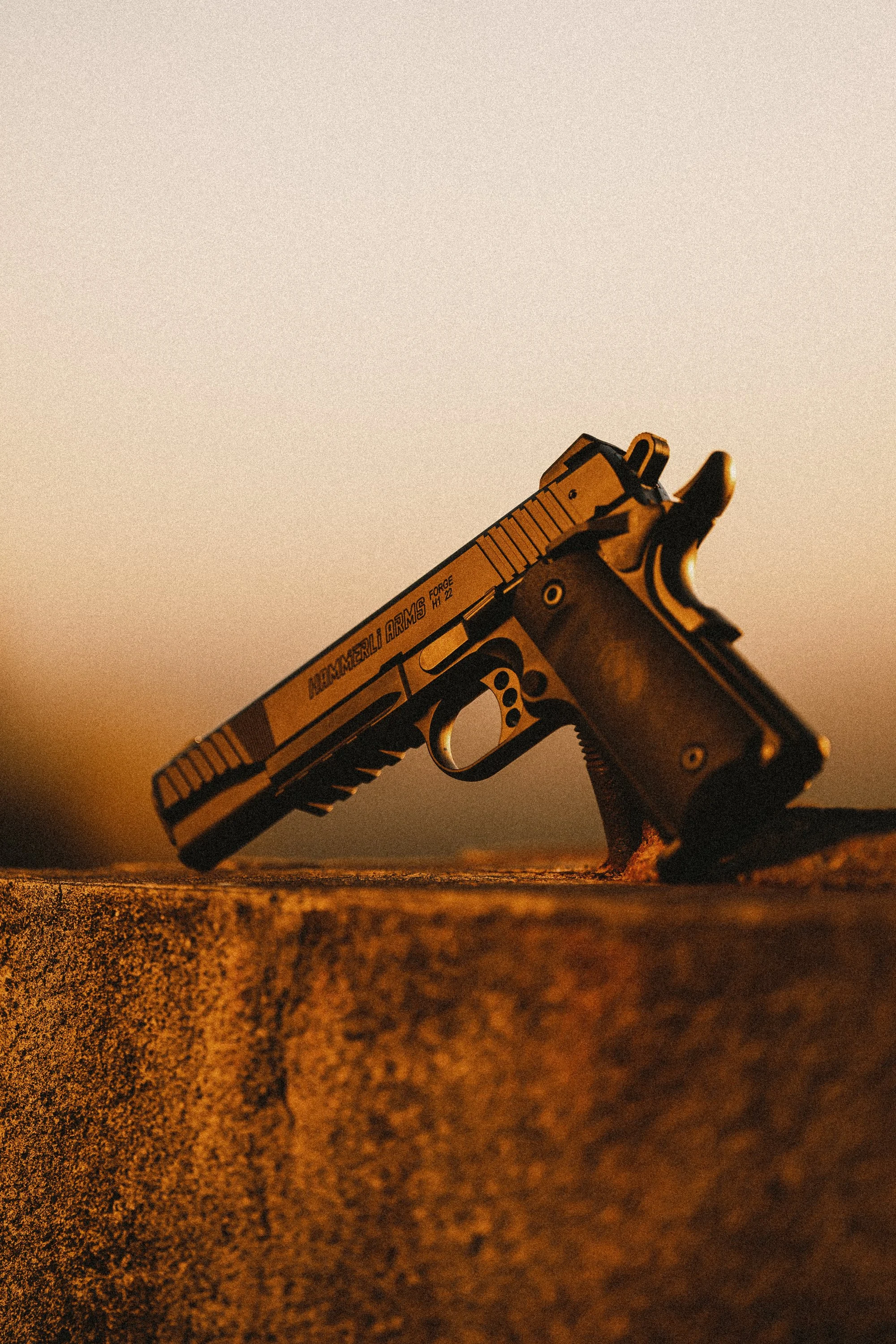 Close-up of a handgun placed on a concrete surface during sunset.