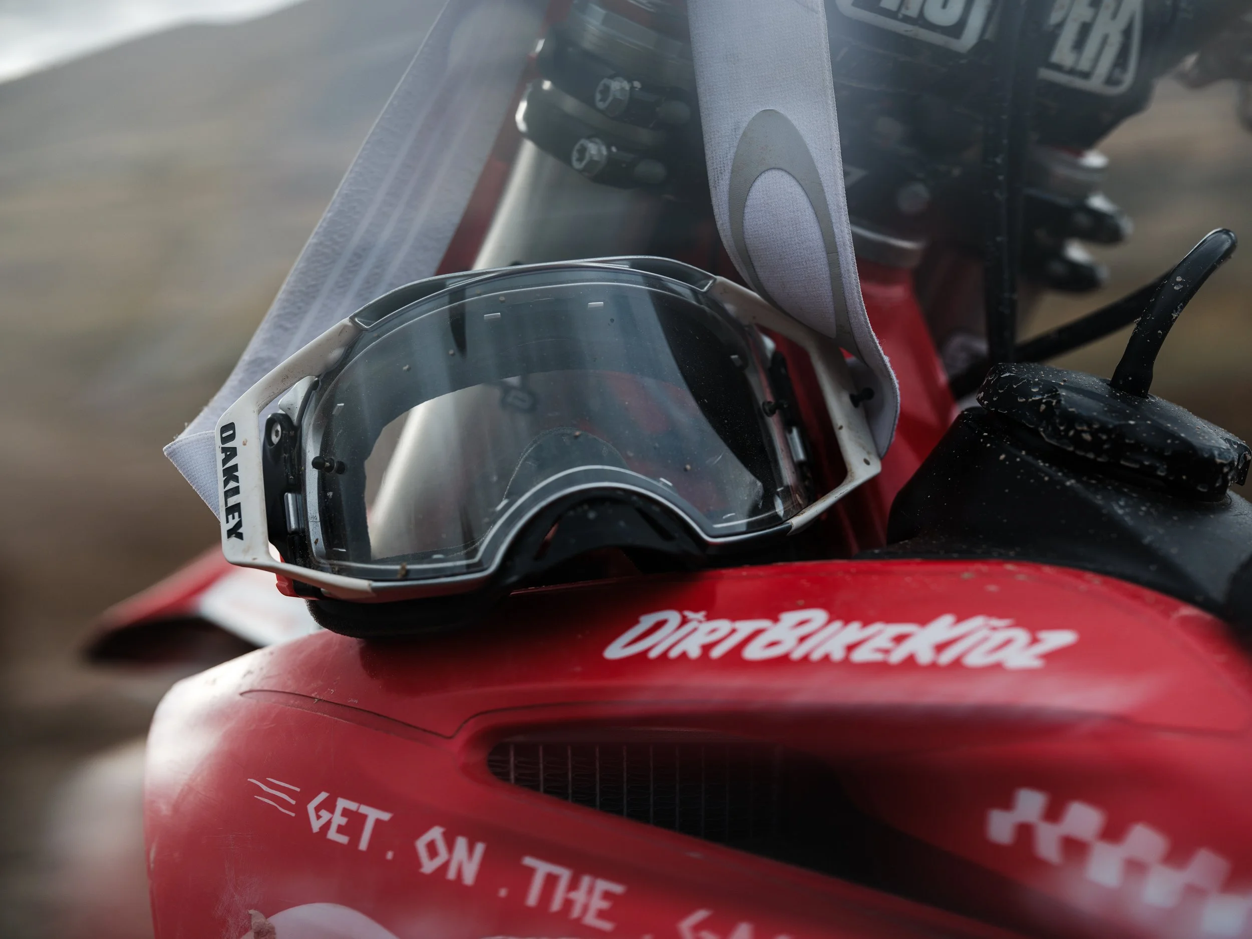 Close-up of motocross goggles resting on a red dirt bike with "DirtBikeKidz" decal.