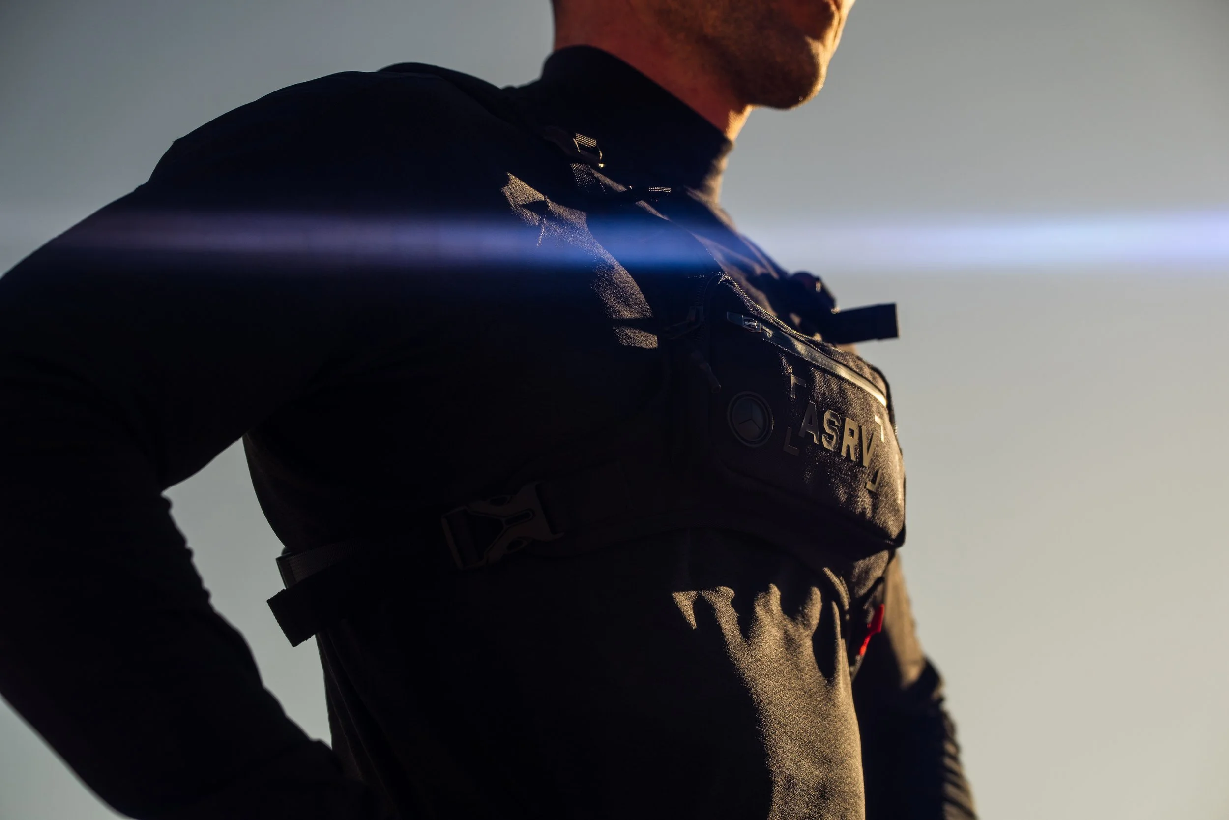 Person wearing a tactical chest rig in low light with a sun flare.