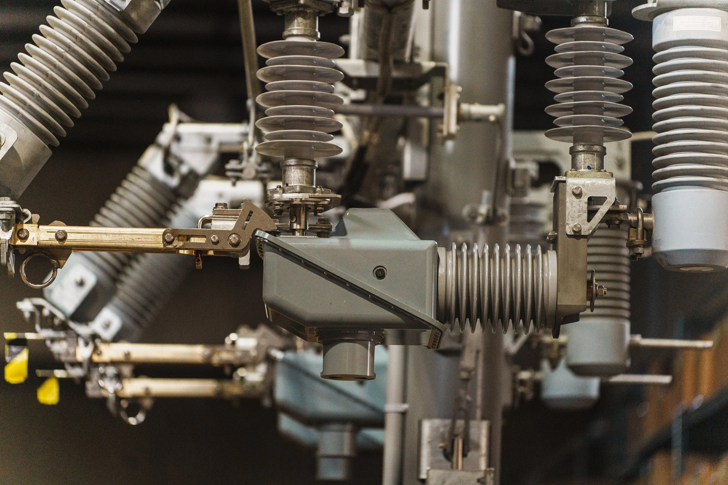 Close-up of electrical switchgear components with insulators and metal connectors in an industrial setting.