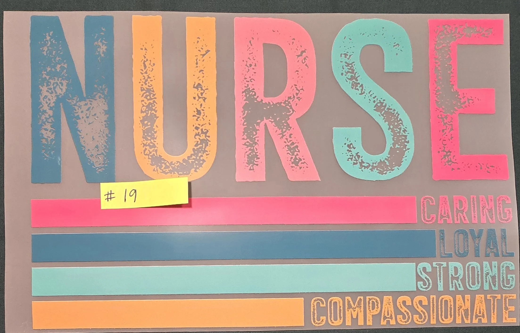 Colorful sign with the word 'NURSE' in large, distressed lettering in blue, orange, pink, and teal. A yellow sticky note with '#19' is attached to the sign.