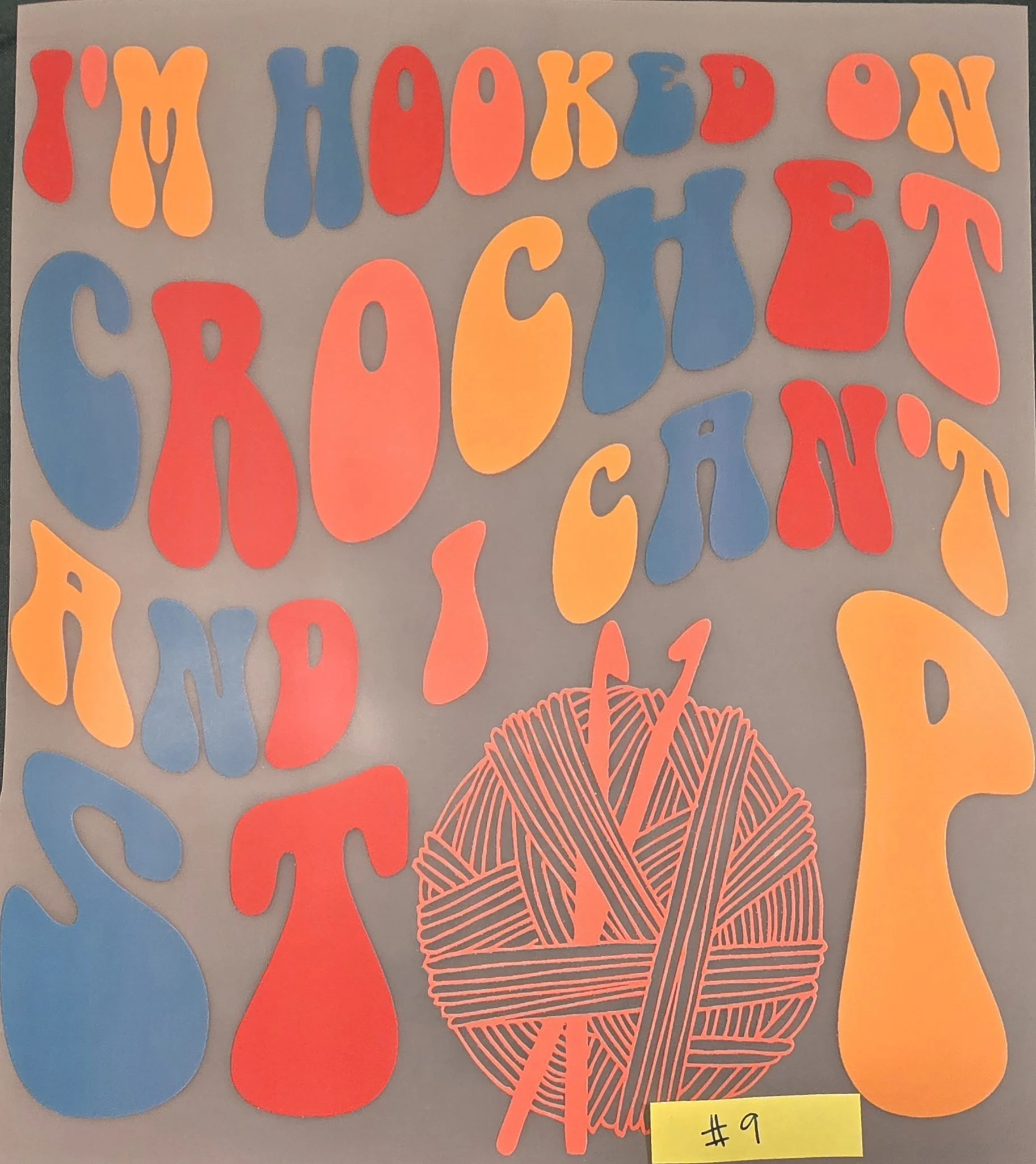 A collection of colorful paper cutouts of knitting and yarn related shapes, with a yellow sticky note labeled '#9' attached at the bottom right corner.