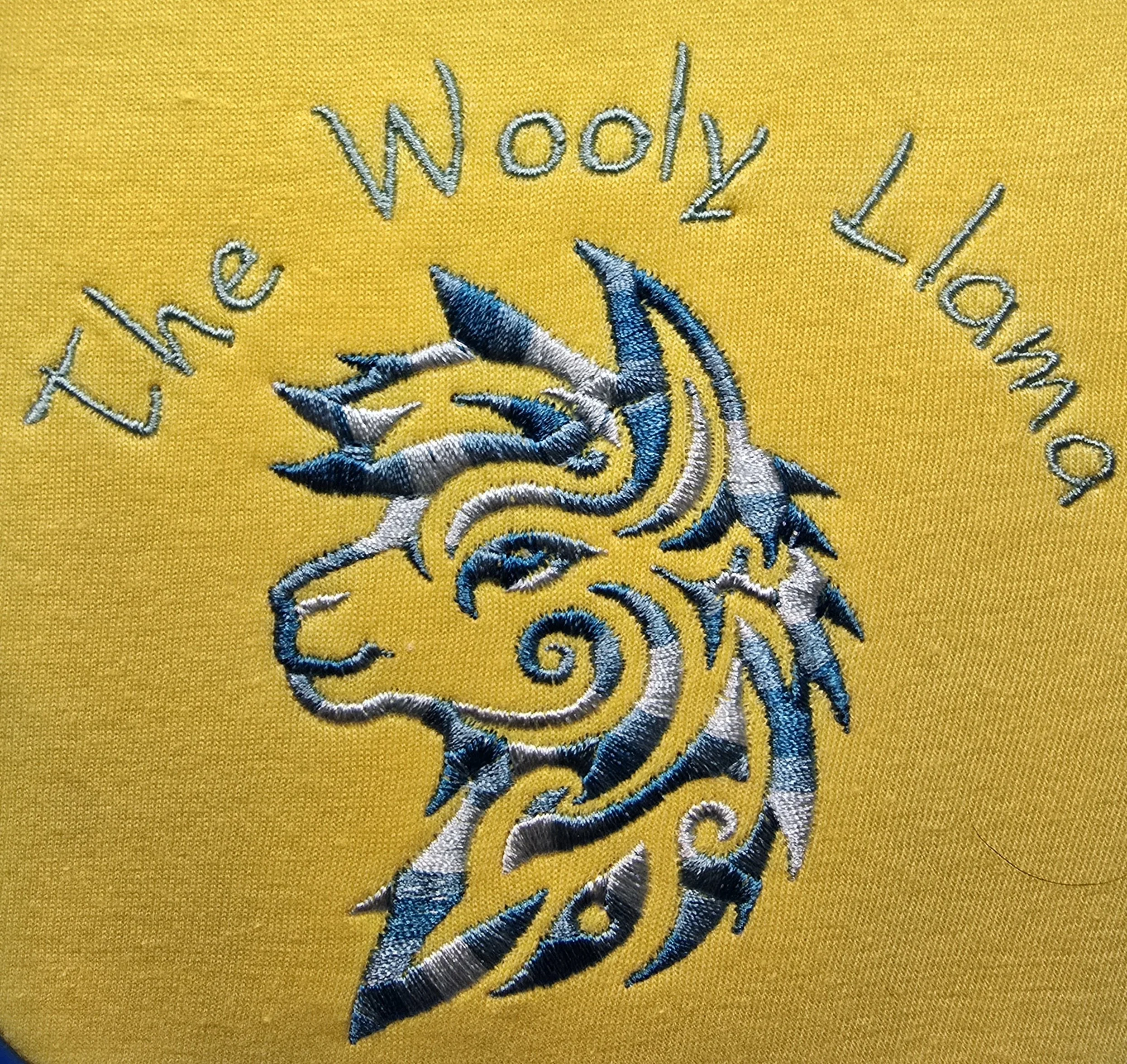 Embroidery of a stylized Lama head with the text 'The Wooly Lama' on a yellow fabric background.