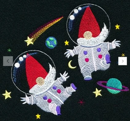 Two embroidered astronauts gnome floating in space surrounded by stars, planets, a shooting star, and the Earth.