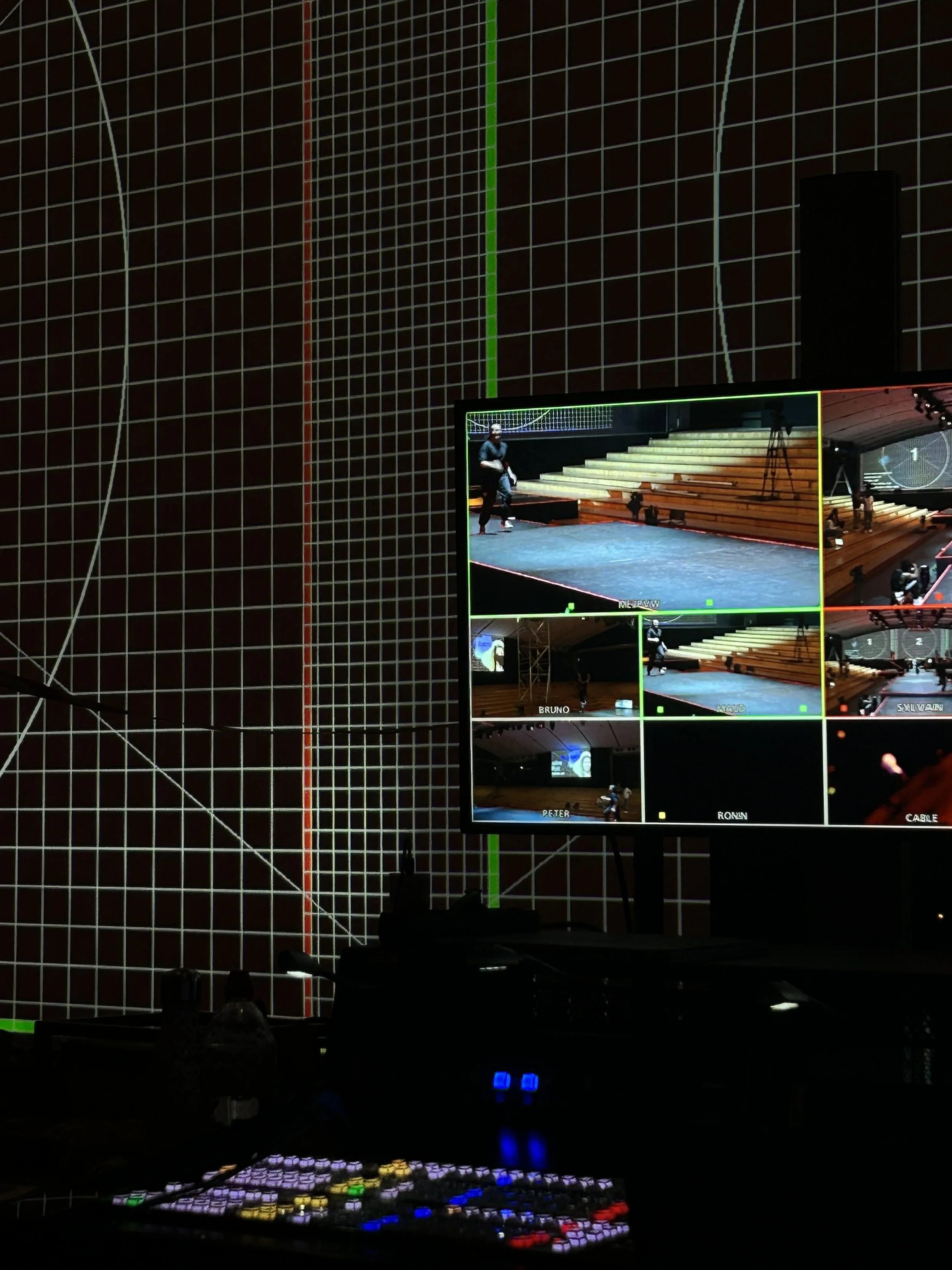 Un écran de contrôle vidéo affichant plusieurs vues d'une scène de spectacle ou de répétition avec des escaliers en bois.