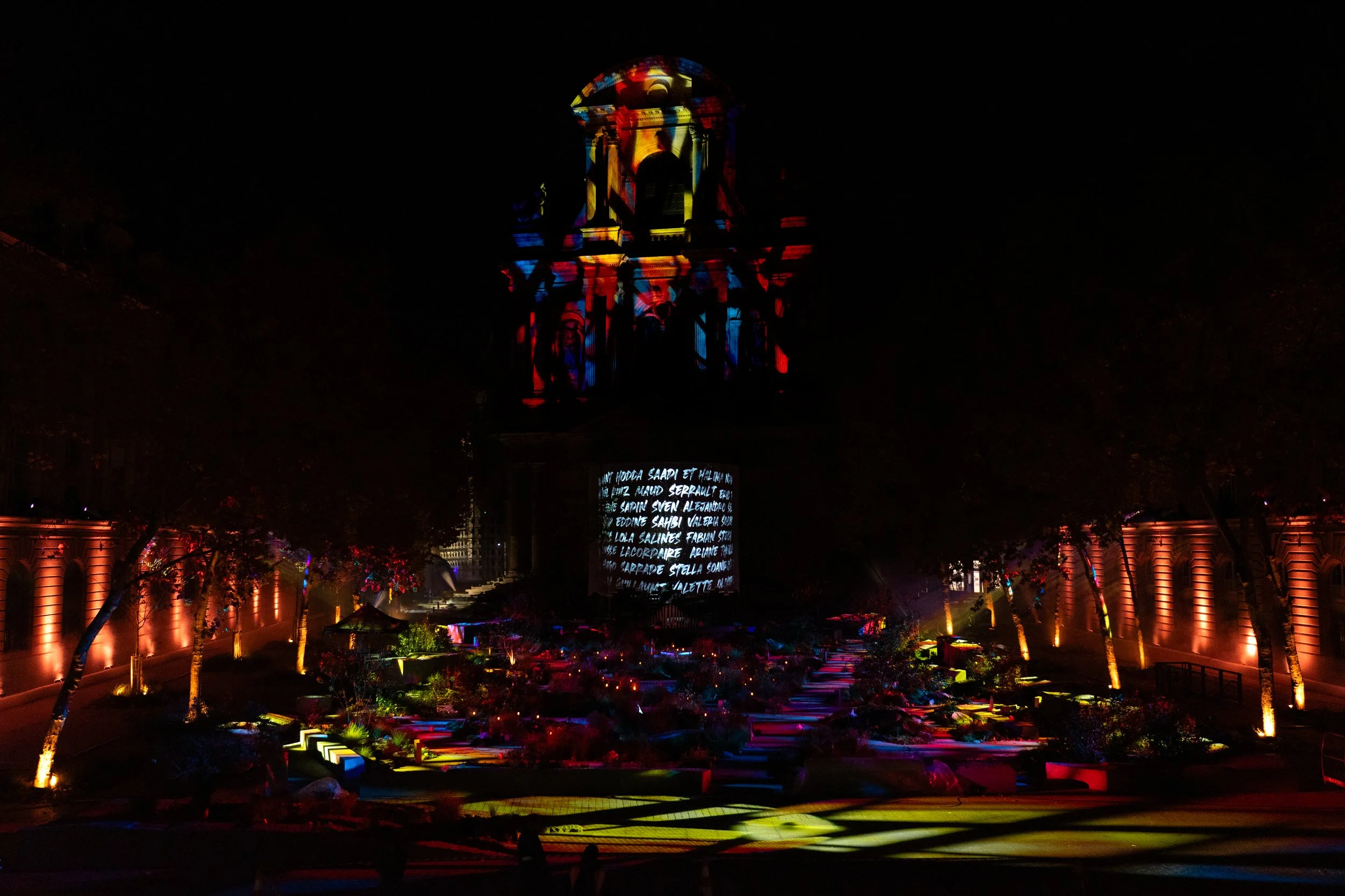 Une projection lumineuse colorée sur une façade de bâtiment historique lors d'un spectacle nocturne.