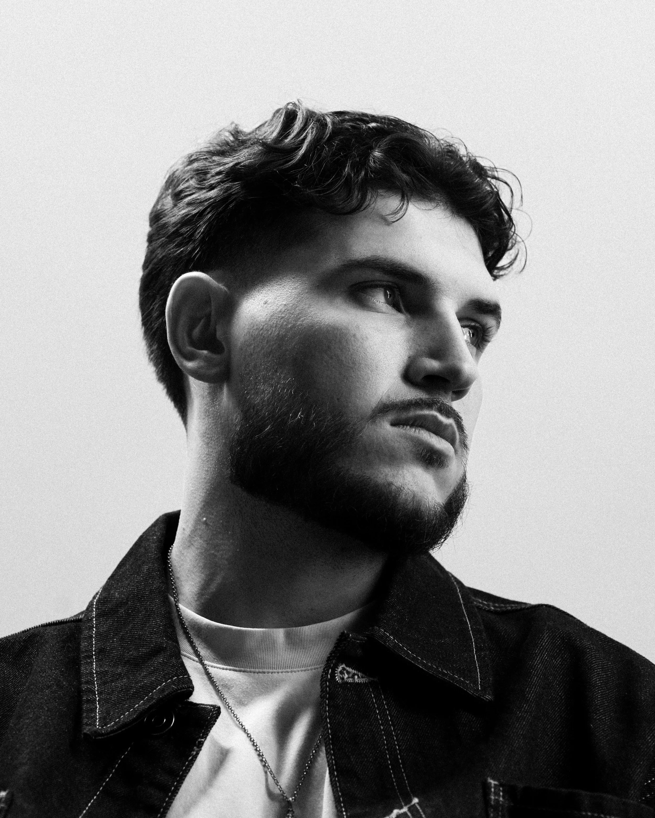 Portrait studio de DJ The Real Fabz ajustant ses lunettes, fond blanc, photographie promotionnelle DJ.