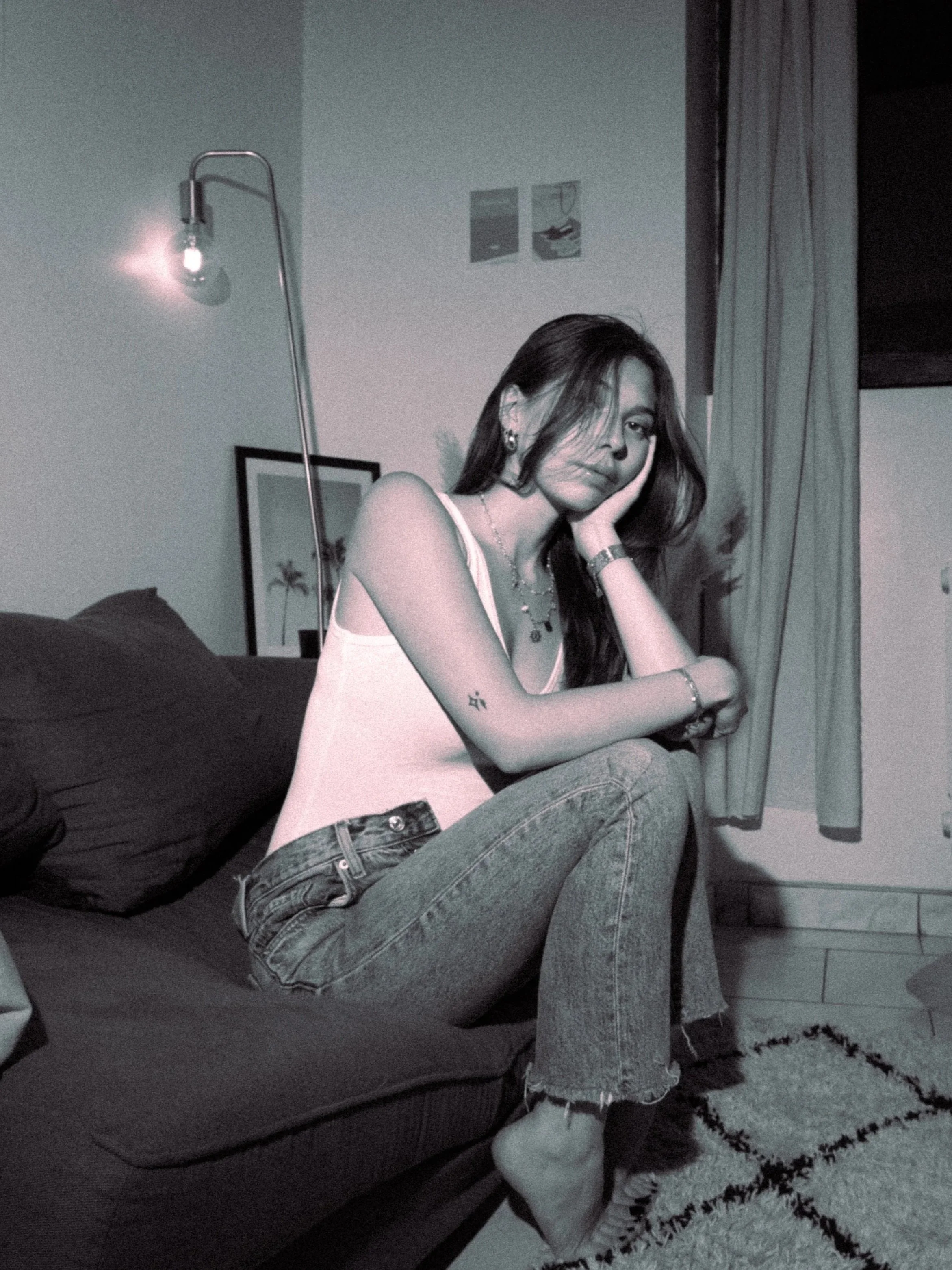 Femme assise sur canapé dans un appartement lyonnais, ambiance nocturne chaleureuse.