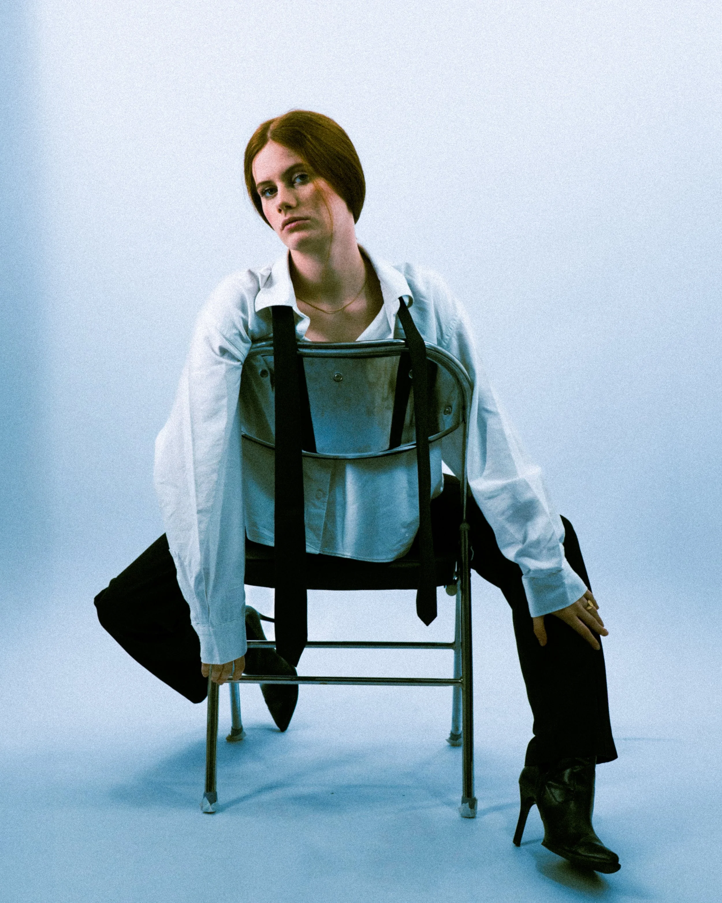 Femme posant sur une chaise en studio, lignes graphiques et élégance éditoriale.