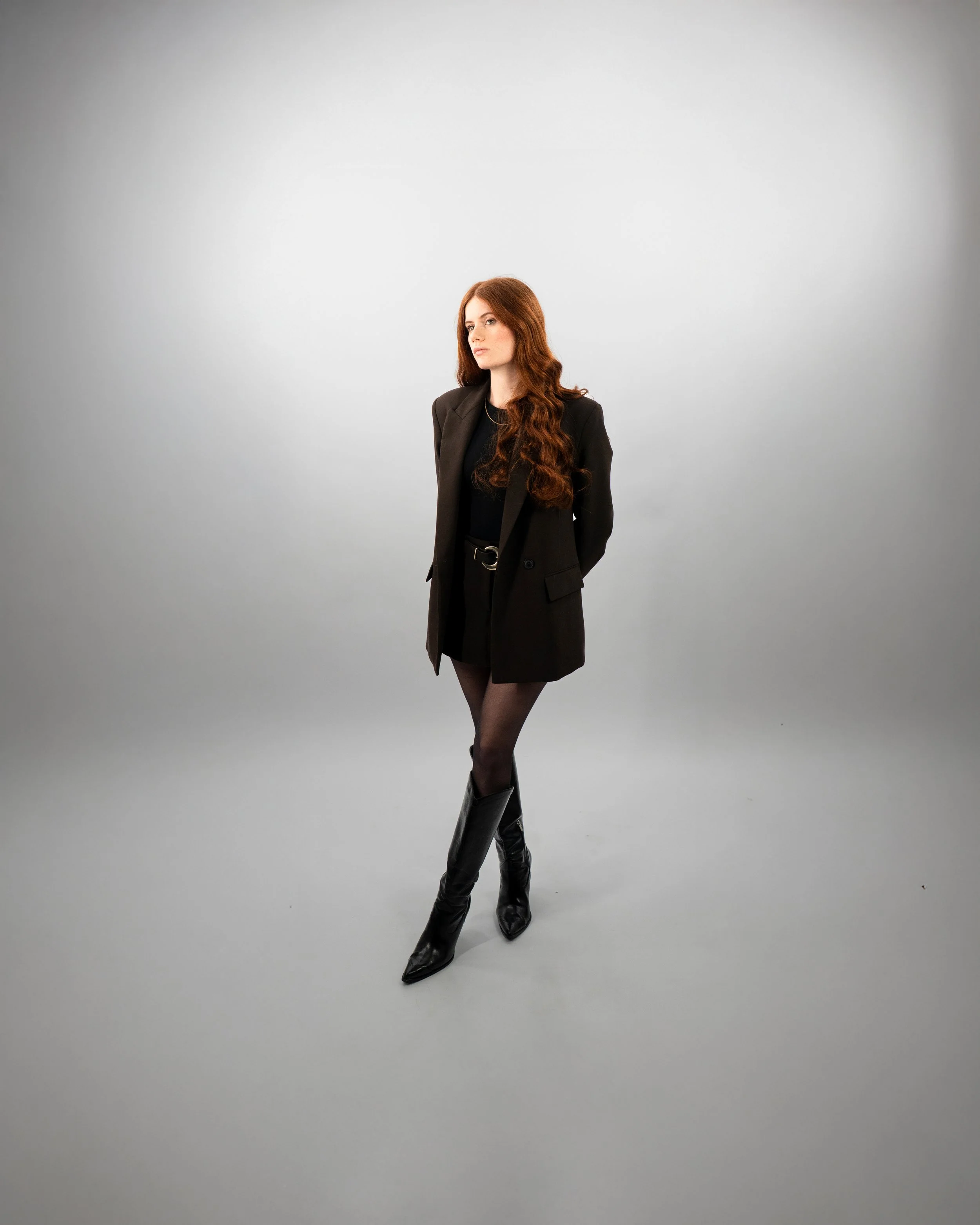 Portrait féminin debout en studio fond blanc, tenue élégante et esthétique minimaliste.