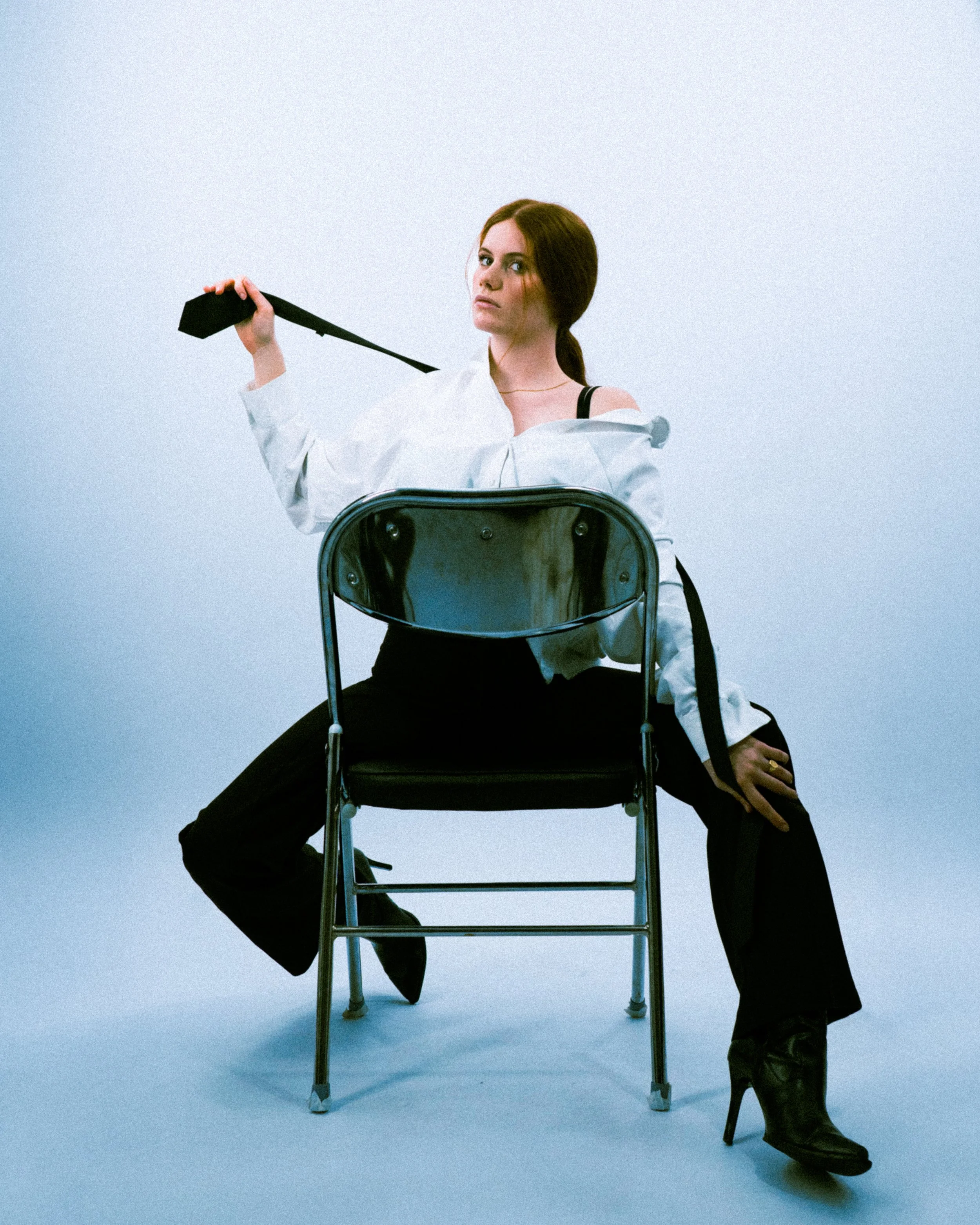 Portrait féminin assis sur chaise en studio, posture élégante et esthétique éditoriale.