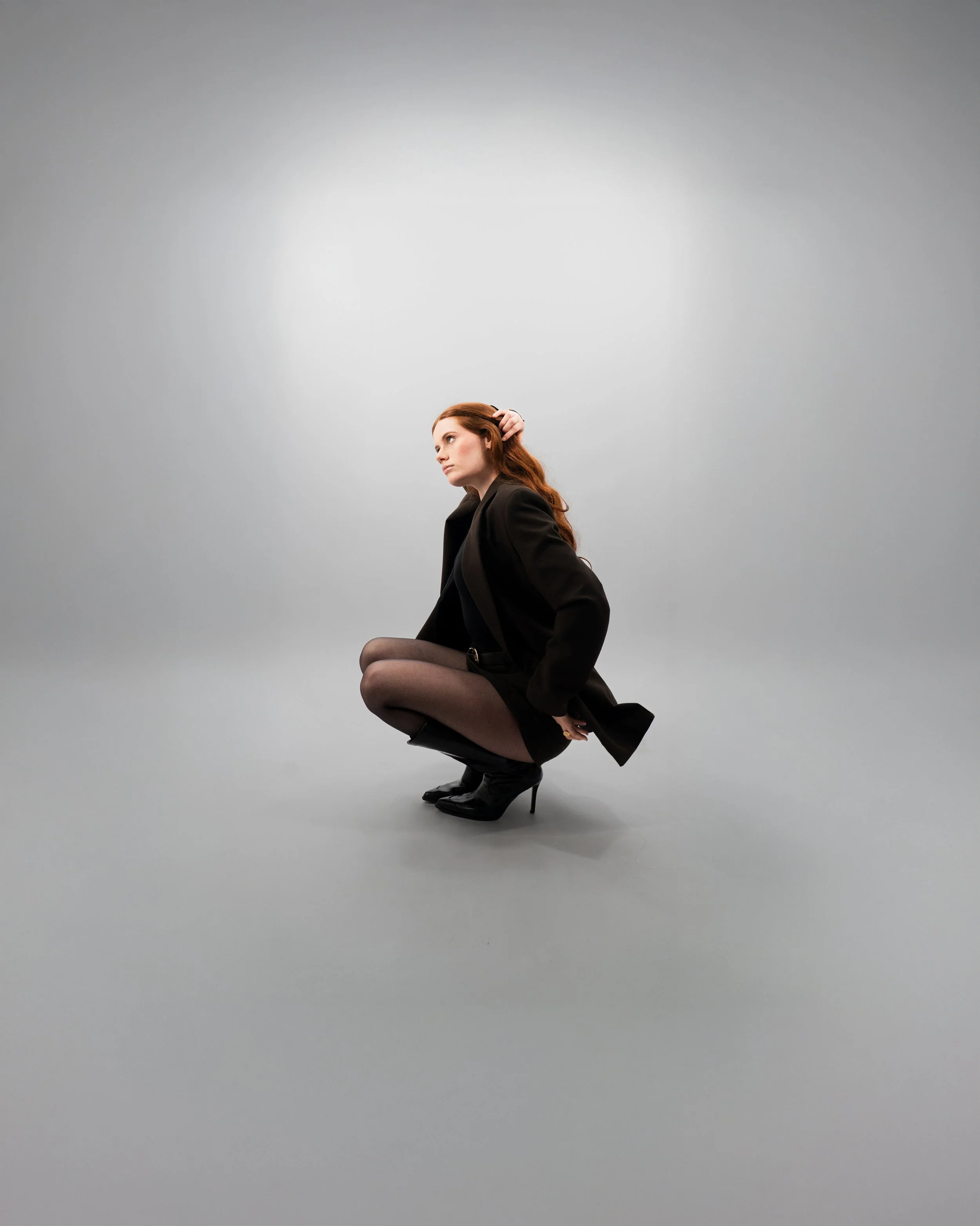 Femme accroupie en studio, posture élégante et lignes du corps travaillées.