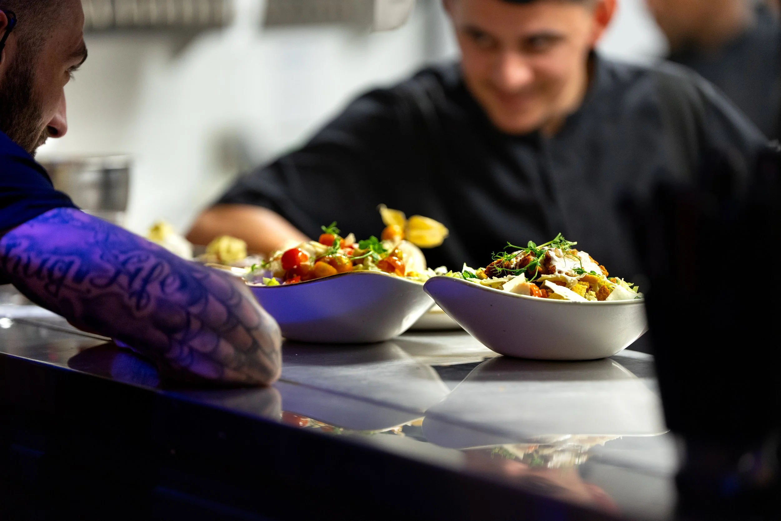 Deux chefs en train de préparer des salades dans une cuisine professionnelle.