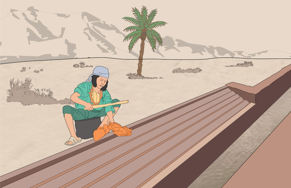 A person working on a railway track in a desert landscape with a palm tree and mountains in the background.